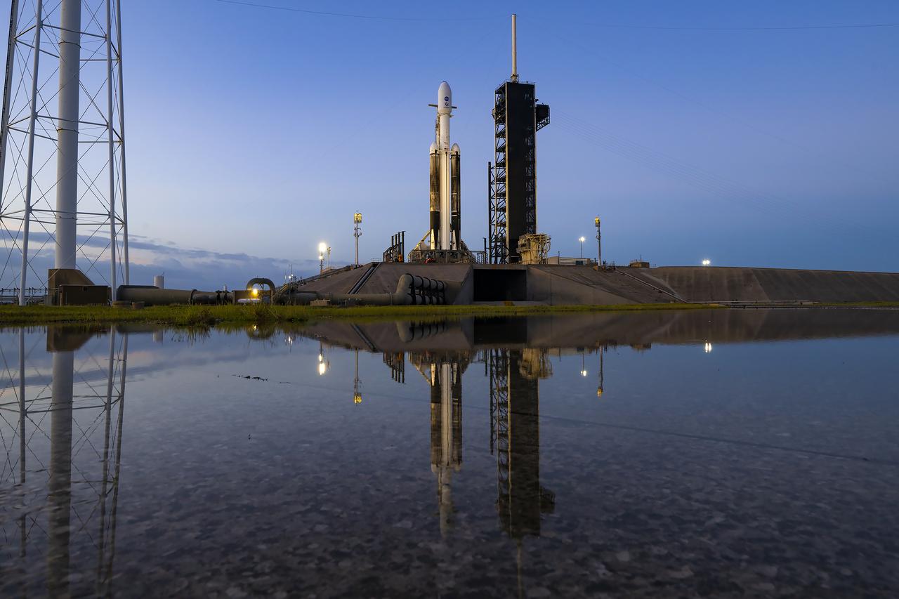 A reflection in the water shows NASA’s Europa Clipper spacecraft atop SpaceX’s Falcon Heavy rocket at Launch Pad 39A on Sunday, Oct. 13, 2024, at the agency’s Kennedy Space Center in Florida ahead of launch to Jupiter’s icy moon, Europa. The spacecraft will complete nearly 50 flybys of Europa to determine if there are conditions suitable for life beyond Earth. Launch is targeting 12:06 p.m. EDT on Monday, Oct. 14, from Launch Complex 39A at Kennedy Space Center in Florida.