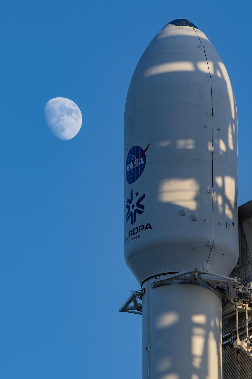 The Earth’s Moon appears with NASA’s Europa Clipper spacecraft encapsulated in a payload fairing atop SpaceX’s Heavy rocket at Launch Complex 39A on Sunday, Oct. 13, 2024, at the agency’s Kennedy Space Center in Florida. The Europa Clipper spacecraft will travel to Jupiter’s icy moon Europa to determine if there are conditions suitable for life beyond Earth.