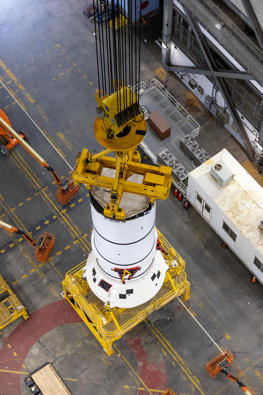 Engineers and technicians with the Exploration Ground Systems Program attach an overhead crane to the left aft assembly, or bottom portion of the solid rocket boosters for the SLS (Space Launch System) rocket inside the Vehicle Assembly Building at NASA’s Kennedy Space Center on Tuesday, Nov. 19, 2024. The crane will lift the aft assembly on top of mobile launcher 1 followed by the right aft assembly and stack the remaining booster segments for the Artemis II mission.