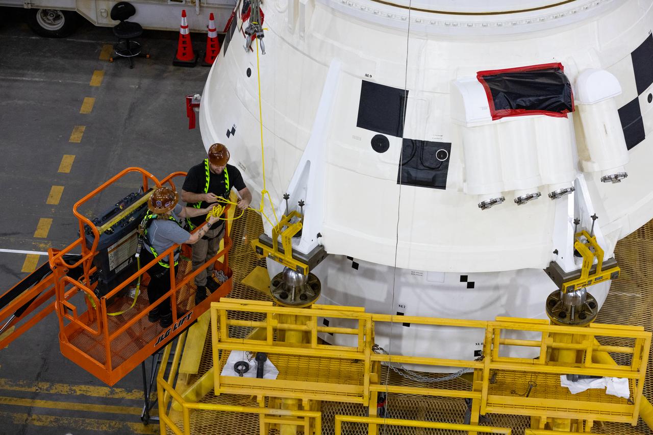 Engineers and technicians with the Exploration Ground Systems Program attach an overhead crane to the left aft assembly, or bottom portion of the solid rocket boosters for the SLS (Space Launch System) rocket, inside the Vehicle Assembly Building at NASA’s Kennedy Space Center on Tuesday, Nov. 19, 2024. The crane will lift the aft assembly on top of mobile launcher 1 followed by the right aft assembly and stack the remaining booster segments for the Artemis II mission.