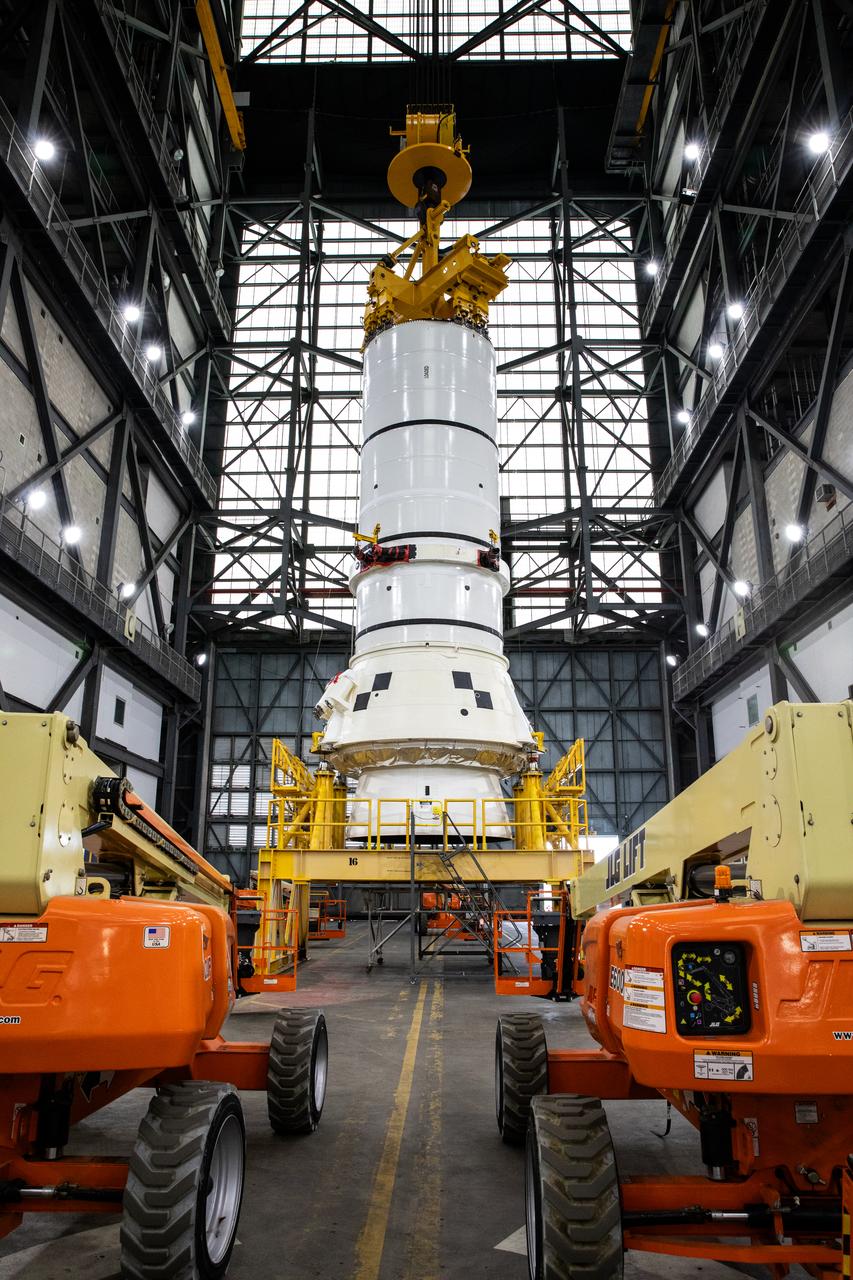 Engineers and technicians with the Exploration Ground Systems Program attach an overhead crane to the left aft assembly, or bottom portion of the solid rocket boosters for the SLS (Space Launch System) rocket, inside the Vehicle Assembly Building at NASA’s Kennedy Space Center on Tuesday, Nov. 19, 2024. The crane will lift the aft assembly on top of mobile launcher 1 followed by the right aft assembly and stack the remaining booster segments for the Artemis II mission.  