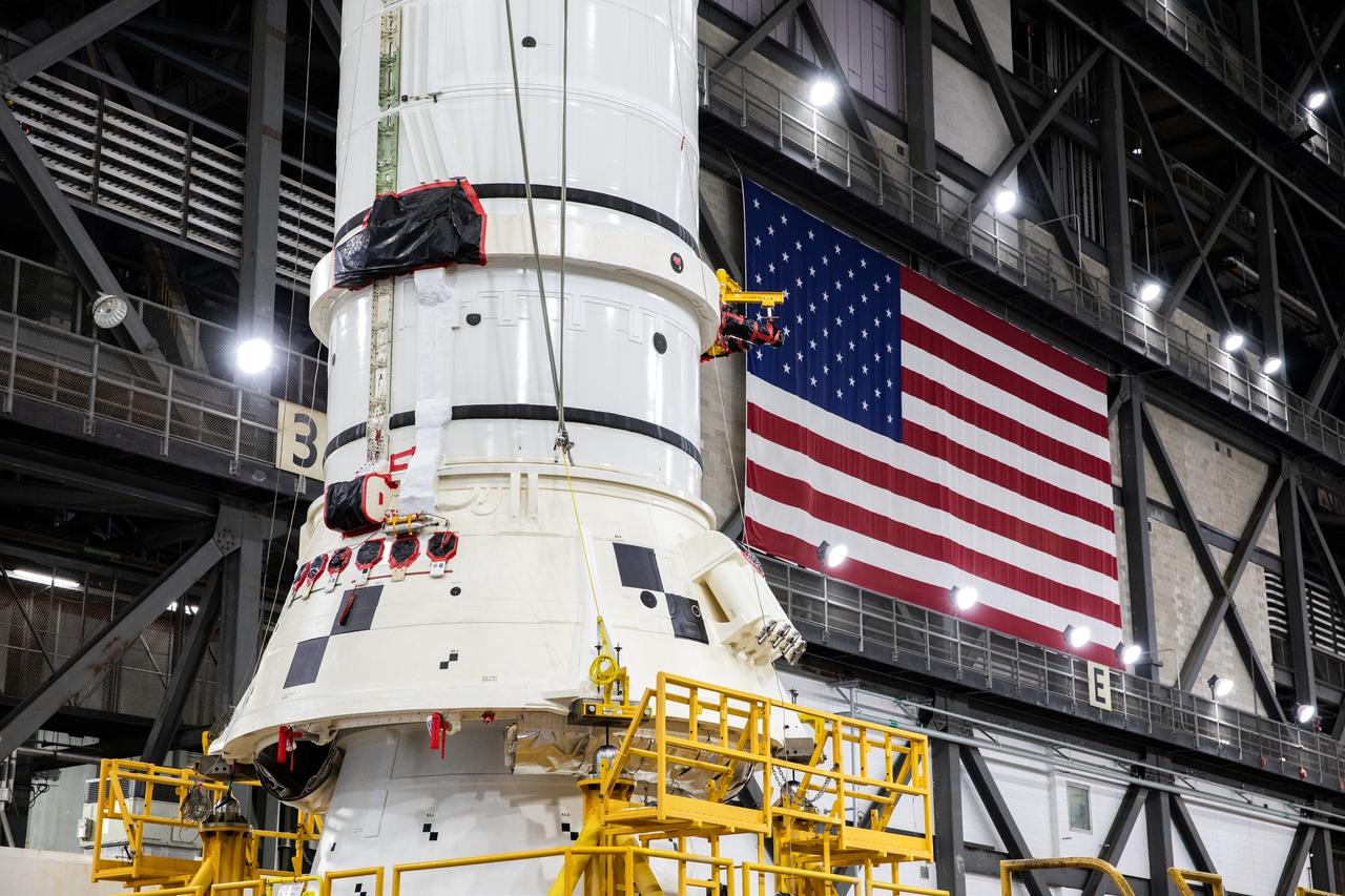 Engineers and technicians with the Exploration Ground Systems Program attach an overhead crane to the left aft assembly, or bottom portion of the solid rocket boosters for the SLS (Space Launch System) rocket, inside the Vehicle Assembly Building at NASA’s Kennedy Space Center on Tuesday, Nov. 19, 2024. The crane will lift the aft assembly on top of mobile launcher 1 followed by the right aft assembly and stack the remaining booster segments for the Artemis II mission.