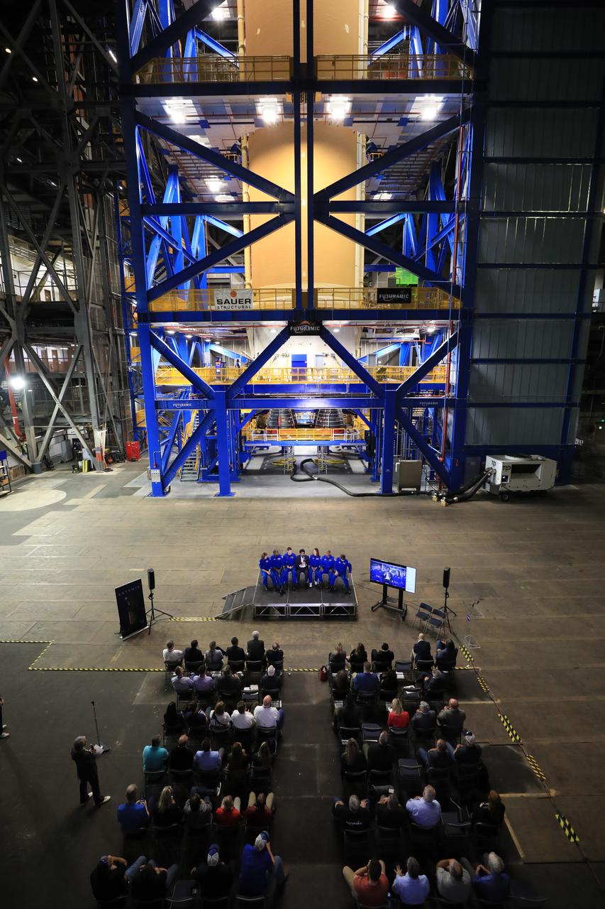 From left, CSA (Canadian Space Agency) astronaut Jenni Gibbons, NASA astronaut Andre Douglas, CSA astronaut Jeremy Hansen, NASA Moon to Mars Program Deputy Associate Administrator Amit Kshatriya, and NASA astronauts Christina Koch, Victor Glover, and Reid Wiseman participate in a media day event on Monday, Dec. 16, 2024, inside the Vehicle Assembly Building at the agency’s Kennedy Space Center in Florida. The Artemis II crew and backup crew participated in the event days after teams with NASA’s Exploration Ground Systems transport lifted the agency’s 212-foot-tall SLS (Space Launch System) core stage from the facility’s transfer aisle into High Bay 2 where it will remain while teams stack the two solid rocket boosters on top of mobile launcher 1.