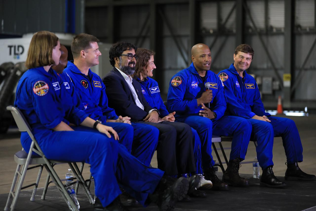From left, CSA (Canadian Space Agency) astronaut Jenni Gibbons, NASA astronaut Andre Douglas, CSA astronaut Jeremy Hansen, NASA Moon to Mars Program Deputy Associate Administrator Amit Kshatriya, and NASA astronauts Christina Koch, Victor Glover, and Reid Wiseman participate in a media day event on Monday, Dec. 16, 2024, inside the Vehicle Assembly Building at the agency’s Kennedy Space Center in Florida. The Artemis II crew and backup crew participated in the event days after teams with NASA’s Exploration Ground Systems transport lifted the agency’s 212-foot-tall SLS (Space Launch System) core stage from the facility’s transfer aisle into High Bay 2 where it will remain while teams stack the two solid rocket boosters on top of mobile launcher 1.