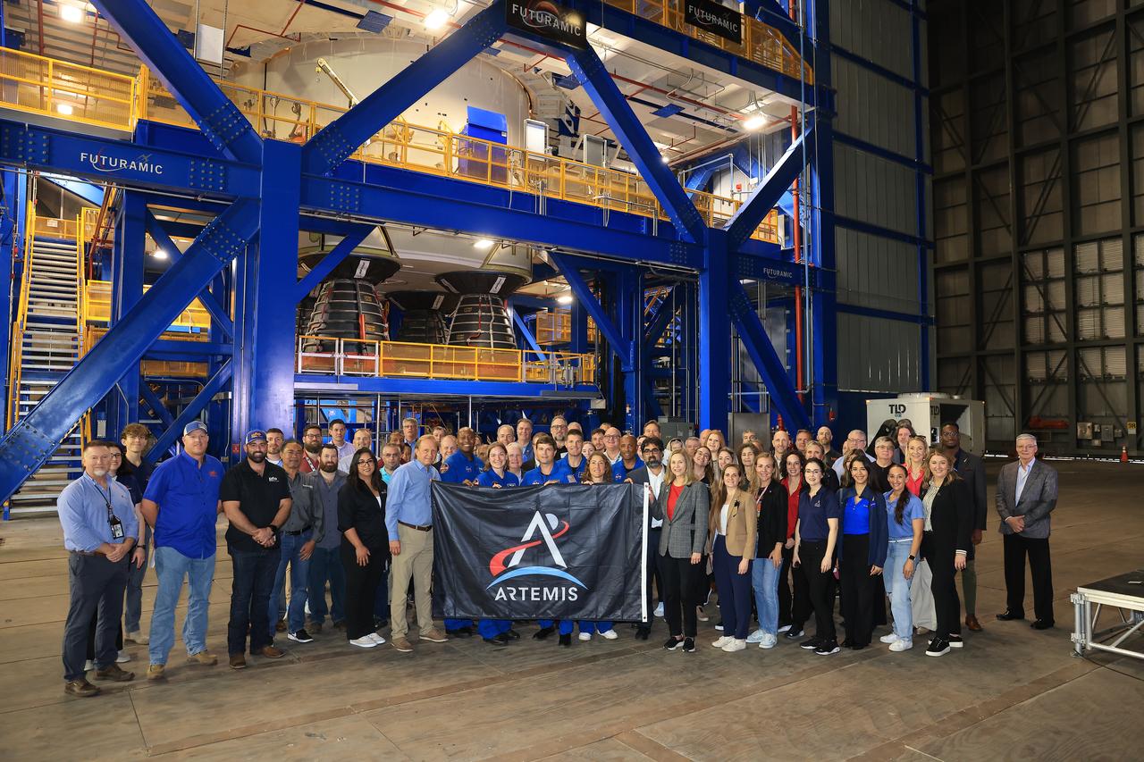 Artemis II crew and backup crew hold a banner with NASA and industry leaders during a supplier and media day event on Monday, Dec. 16, 2024, inside the Vehicle Assembly Building at the agency’s Kennedy Space Center in Florida. The Artemis II crew and backup crew participated in the event days after teams with NASA’s Exploration Ground Systems transport lifted the agency’s 212-foot-tall SLS (Space Launch System) core stage from the facility’s transfer aisle into High Bay 2 where it will remain while teams stack the two solid rocket boosters on top of mobile launcher 1.