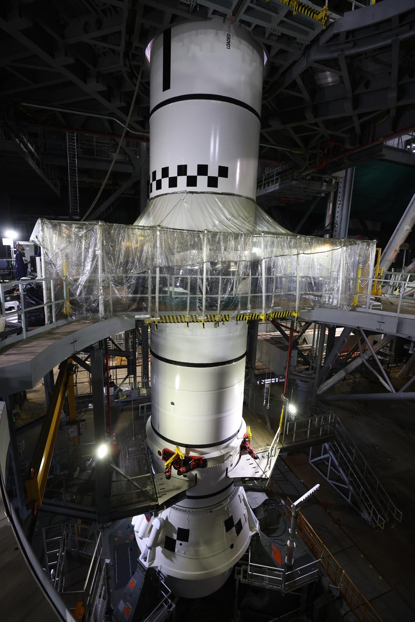Engineers and technicians with the Exploration Ground Systems Program stack the next solid rocket booster segment, the left aft center, on the for the Artemis II SLS (Space Launch System) Moon rocket onto mobile launcher 1 inside the Vehicle Assembly Building’s High Bay 3 at NASA’s Kennedy Space Center on Thursday, Dec. 19, 2024. Once assembled, the boosters will help support the remaining rocket components and the Orion spacecraft during final assembly of the Artemis II Moon rocket and provide more than 75 percent of the total SLS thrust during liftoff from NASA Kennedy’s Launch Pad 39B.