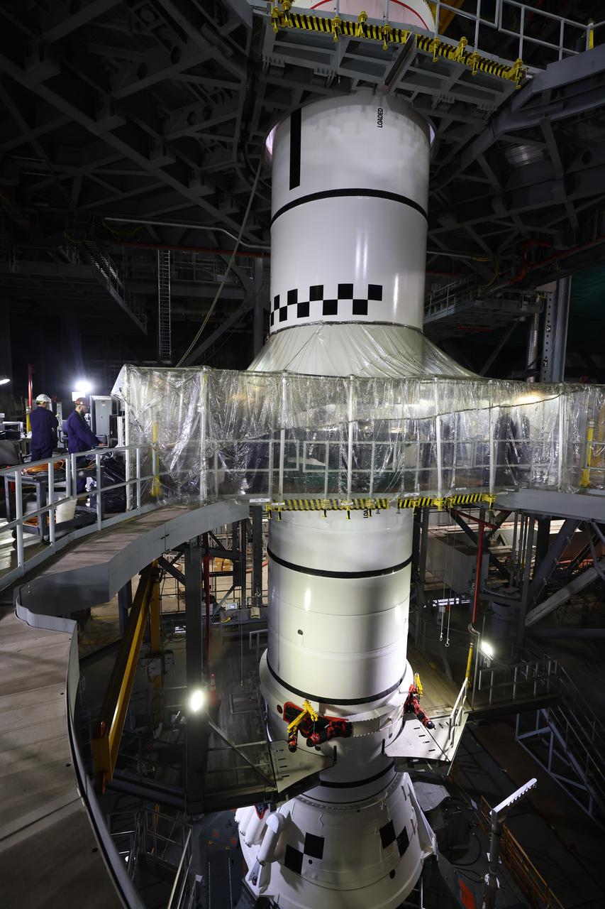Engineers and technicians with the Exploration Ground Systems Program stack the next solid rocket booster segment, the left aft center, on the for the Artemis II SLS (Space Launch System) Moon rocket onto mobile launcher 1 inside the Vehicle Assembly Building’s High Bay 3 at NASA’s Kennedy Space Center on Thursday, Dec. 19, 2024. Once assembled, the boosters will help support the remaining rocket components and the Orion spacecraft during final assembly of the Artemis II Moon rocket and provide more than 75 percent of the total SLS thrust during liftoff from NASA Kennedy’s Launch Pad 39B.