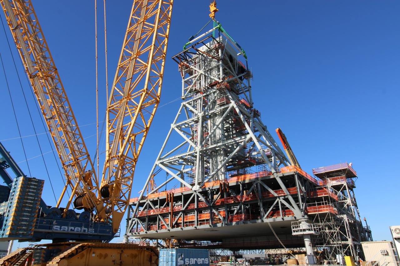 Teams at Bechtel National, Inc. use a crane to lift Module 4 into place atop the mobile launcher 2 tower chair at its Kennedy Space Center park site on January 3, 2025. Module 4 is the first of seven modules that will be stacked vertically to make up the almost 400-foot launch tower that will be used beginning with the Artemis IV mission.