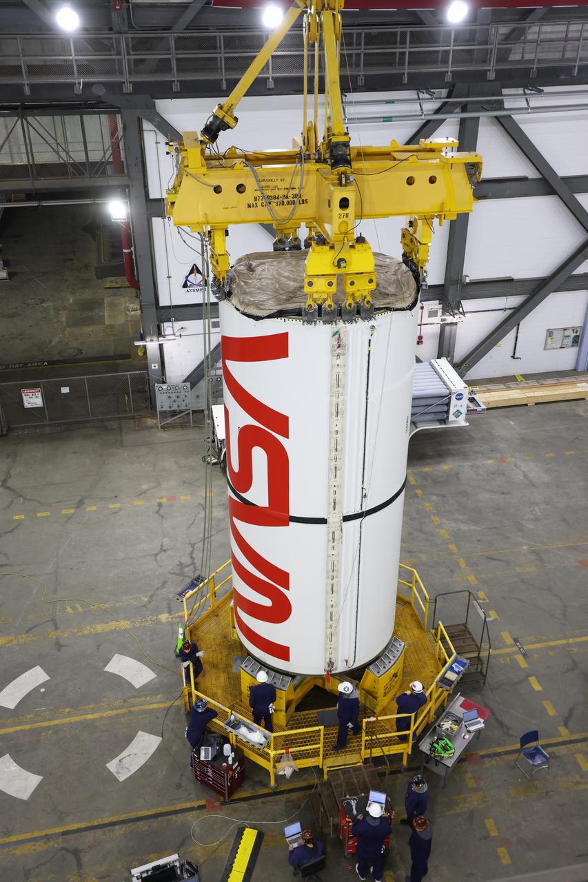 Engineers and technicians with NASA’s Exploration Ground Systems Program transfer the right center center segment with the NASA worm insignia to the Vehicle Assembly Building at NASA's Kennedy Space Center in Florida on Tuesday, Jan. 14, 2025. The booster segment is shown attached to a lifting beam ahead of integration onto the mobile launcher. The boosters will help support the remaining rocket components and the Orion spacecraft during final assembly of the Artemis II Moon rocket and provide more than 75 percent of the total SLS (Space Launch System) thrust during liftoff from NASA Kennedy’s Launch Pad 39B.