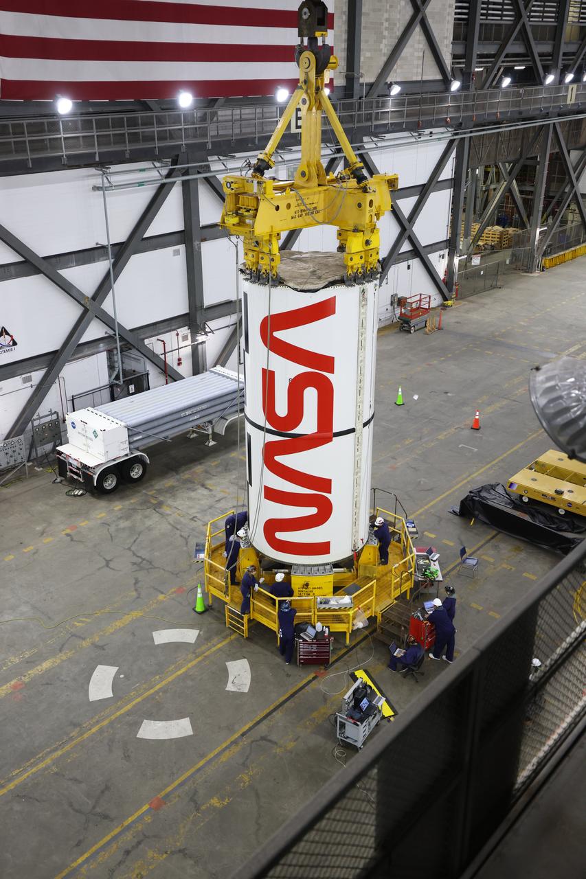 Engineers and technicians with NASA’s Exploration Ground Systems Program transfer the right center center segment with the NASA worm insignia to the Vehicle Assembly Building at NASA's Kennedy Space Center in Florida on Tuesday, Jan. 14, 2025. The booster segment is shown attached to a lifting beam ahead of integration onto the mobile launcher. The boosters will help support the remaining rocket components and the Orion spacecraft during final assembly of the Artemis II Moon rocket and provide more than 75 percent of the total SLS (Space Launch System) thrust during liftoff from NASA Kennedy’s Launch Pad 39B.