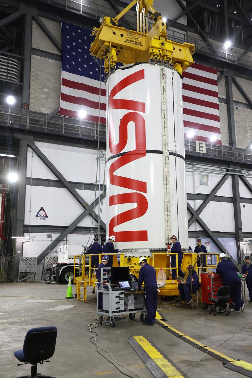 Engineers and technicians with NASA’s Exploration Ground Systems Program transfer the right center center segment with the NASA worm insignia to the Vehicle Assembly Building at NASA's Kennedy Space Center in Florida on Tuesday, Jan. 14, 2025. The booster segment is shown attached to a lifting beam ahead of integration onto the mobile launcher. The boosters will help support the remaining rocket components and the Orion spacecraft during final assembly of the Artemis II Moon rocket and provide more than 75 percent of the total SLS (Space Launch System) thrust during liftoff from NASA Kennedy’s Launch Pad 39B.
