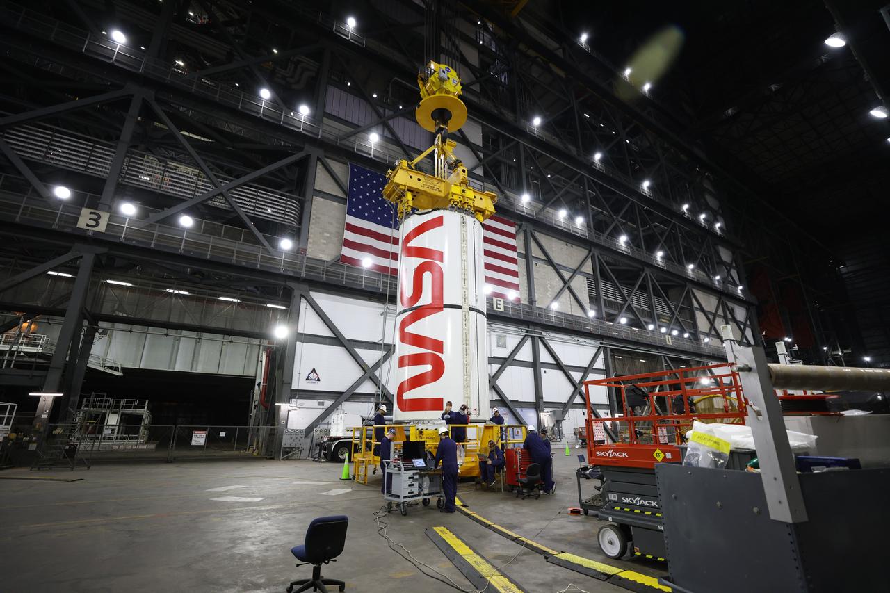 Engineers and technicians with NASA’s Exploration Ground Systems Program transfer the right center center segment with the NASA worm insignia to the Vehicle Assembly Building at NASA's Kennedy Space Center in Florida on Tuesday, Jan. 14, 2025. The booster segment is shown attached to a lifting beam ahead of integration onto the mobile launcher. The boosters will help support the remaining rocket components and the Orion spacecraft during final assembly of the Artemis II Moon rocket and provide more than 75 percent of the total SLS (Space Launch System) thrust during liftoff from NASA Kennedy’s Launch Pad 39B.