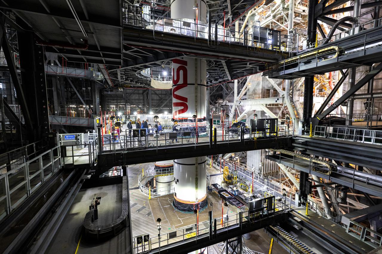 Inside High Bay 3 of the Vehicle Assembly Building at NASA’s Kennedy Space Center in Florida, technicians with the agency’s Exploration Ground Systems use a crane to lower the right forward center booster segment for the NASA’s SLS (Space Launch System) rocket onto the right center center segment with the iconic NASA “worm” insignia atop the mobile launcher on Monday, Jan. 27, 2025. The boosters will help support the remaining rocket components and the Orion spacecraft during final assembly of the Artemis II Moon rocket and provide more than 75 percent of the total SLS thrust during liftoff from NASA Kennedy’s Launch Pad 39B.