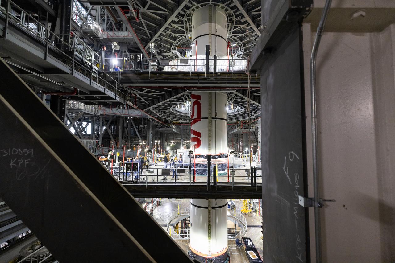Inside High Bay 3 of the Vehicle Assembly Building at NASA’s Kennedy Space Center in Florida, technicians with the agency’s Exploration Ground Systems use a crane to lower the right forward center booster segment for the NASA’s SLS (Space Launch System) rocket onto the right center center segment with the iconic NASA “worm” insignia atop the mobile launcher on Monday, Jan. 27, 2025. The boosters will help support the remaining rocket components and the Orion spacecraft during final assembly of the Artemis II Moon rocket and provide more than 75 percent of the total SLS thrust during liftoff from NASA Kennedy’s Launch Pad 39B.