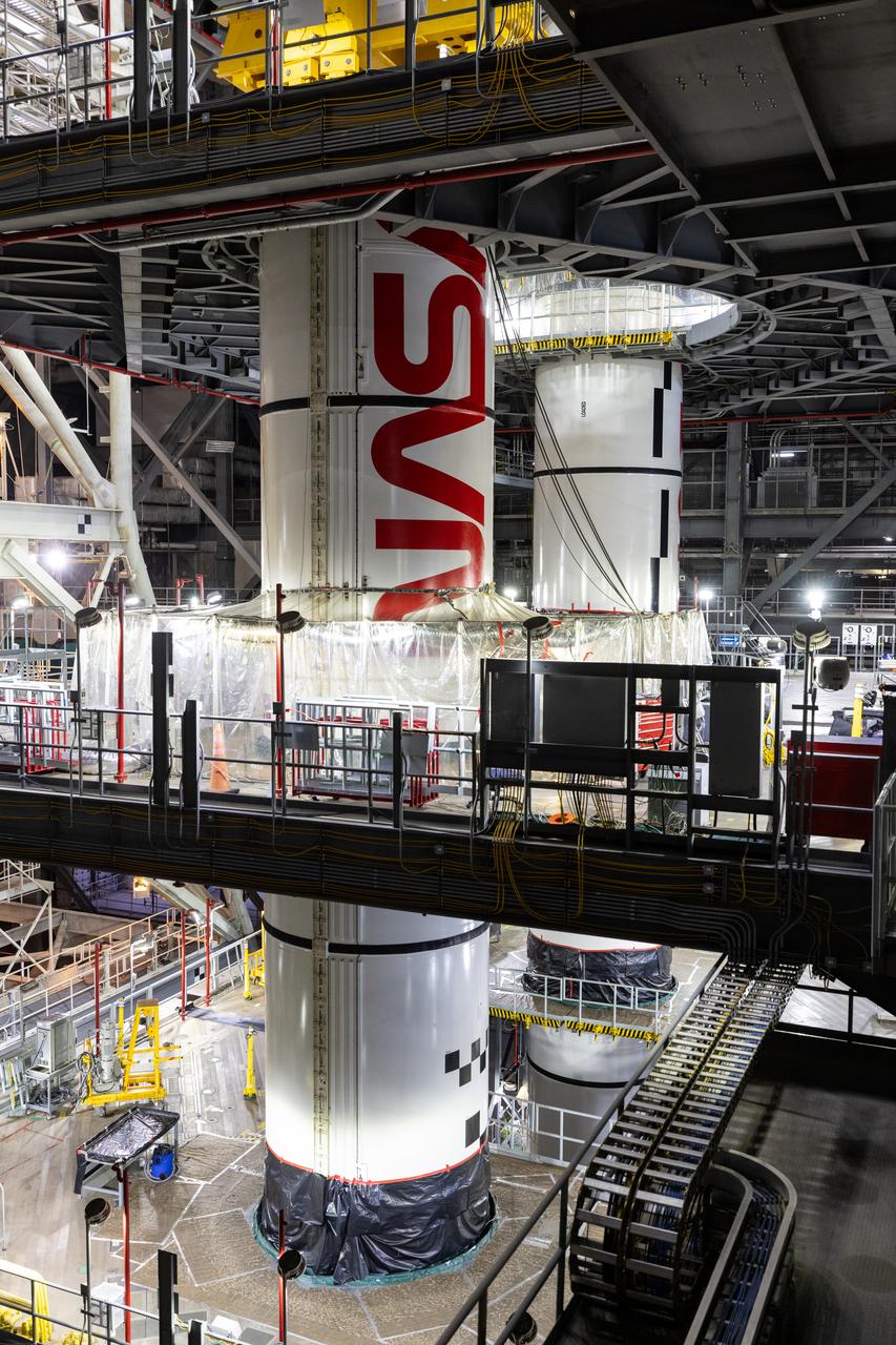 Inside High Bay 3 of the Vehicle Assembly Building at NASA’s Kennedy Space Center in Florida, technicians with the agency’s Exploration Ground Systems use a crane to lower the left center center booster segment for the NASA’s SLS (Space Launch System) rocket onto the left aft center segment atop the mobile launcher on Monday, Jan. 27, 2025. The NASA “worm” insignia can be seen on both the center center booster segments. The boosters will help support the remaining rocket components and the Orion spacecraft during final assembly of the Artemis II Moon rocket and provide more than 75 percent of the total SLS thrust during liftoff from NASA Kennedy’s Launch Pad 39B.