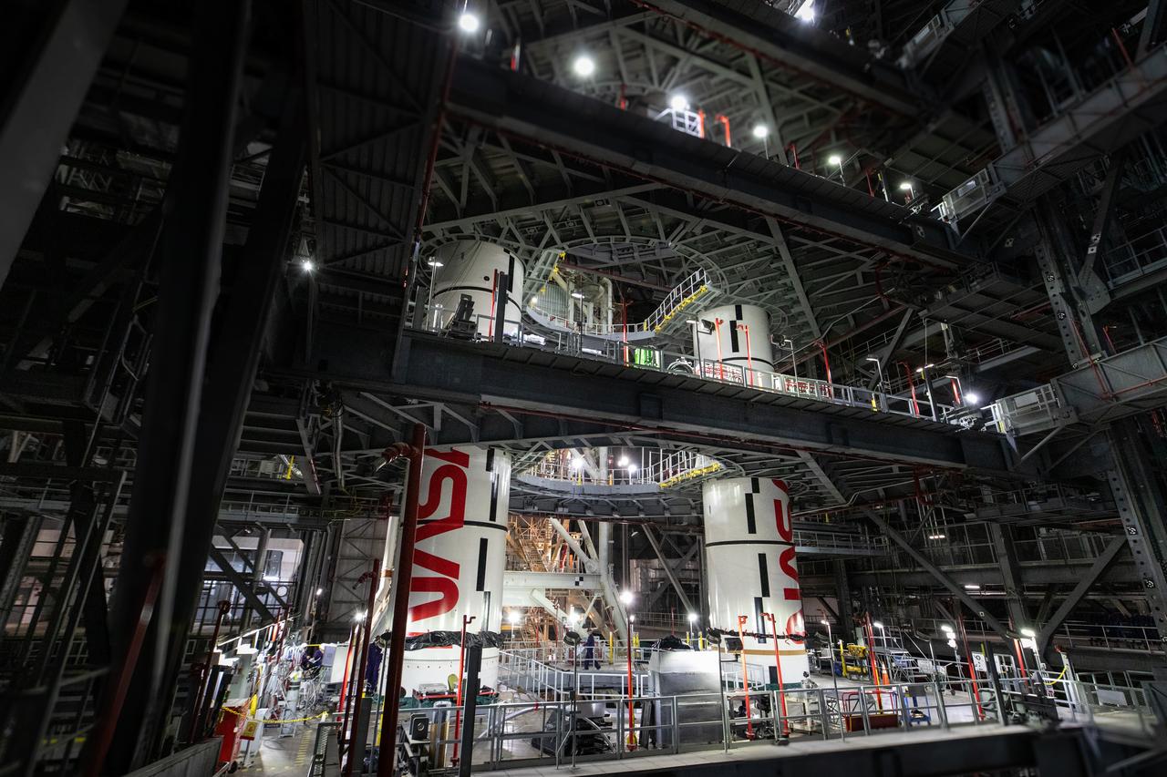 Inside High Bay 3 of the Vehicle Assembly Building at NASA’s Kennedy Space Center in Florida, technicians with the agency’s Exploration Ground Systems integrate the left forward center booster segment for the NASA’s SLS (Space Launch System) rocket onto the left center center segment atop the mobile launcher on Thursday, Jan. 30, 2025. The NASA “worm” insignia can be seen on both the center center booster segments. The boosters will help support the remaining rocket components and the Orion spacecraft during final assembly of the Artemis II Moon rocket and provide more than 75 percent of the total SLS thrust during liftoff from NASA Kennedy’s Launch Pad 39B.