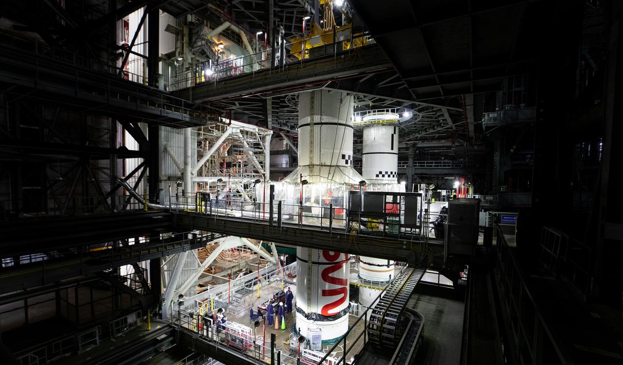 Inside High Bay 3 of the Vehicle Assembly Building at NASA’s Kennedy Space Center in Florida, technicians with the agency’s Exploration Ground Systems integrate the left forward center booster segment for the NASA’s SLS (Space Launch System) rocket onto the left center center segment atop the mobile launcher on Thursday, Jan. 30, 2025. The NASA “worm” insignia can be seen on both the center center booster segments. The boosters will help support the remaining rocket components and the Orion spacecraft during final assembly of the Artemis II Moon rocket and provide more than 75 percent of the total SLS thrust during liftoff from NASA Kennedy’s Launch Pad 39B.