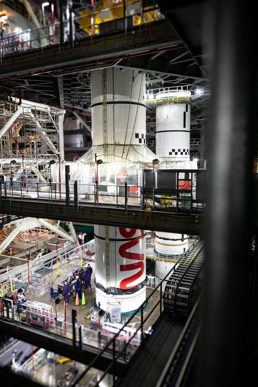 Inside High Bay 3 of the Vehicle Assembly Building at NASA’s Kennedy Space Center in Florida, technicians with the agency’s Exploration Ground Systems integrate the left forward center booster segment for the NASA’s SLS (Space Launch System) rocket onto the left center center segment atop the mobile launcher on Thursday, Jan. 30, 2025. The NASA “worm” insignia can be seen on both the center center booster segments. The boosters will help support the remaining rocket components and the Orion spacecraft during final assembly of the Artemis II Moon rocket and provide more than 75 percent of the total SLS thrust during liftoff from NASA Kennedy’s Launch Pad 39B.