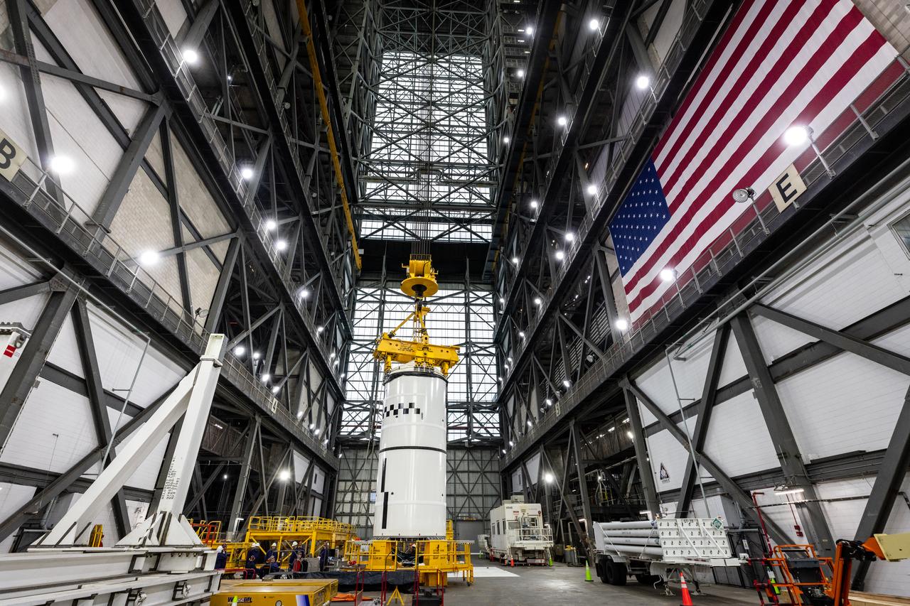 Technicians with NASA’s Exploration Ground Systems use a crane in the transfer aisle of the Vehicle Assembly Building at the agency’s Kennedy Space Center in Florida to prepare to lift the left forward segment for NASA’s SLS (Space Launch System) Moon rocket boosters on Wednesday, Feb. 5, 2025. The left forward segment will be transferred into High Bay 3 where it will be attached to the center forward segment on mobile launcher 1. The twin solid boosters, five segments on each side, will help support the remaining rocket components and the Orion spacecraft during final assembly of the Artemis II Moon rocket and provide more than 75 percent of the total SLS thrust during liftoff from NASA Kennedy’s Launch Pad 39B.