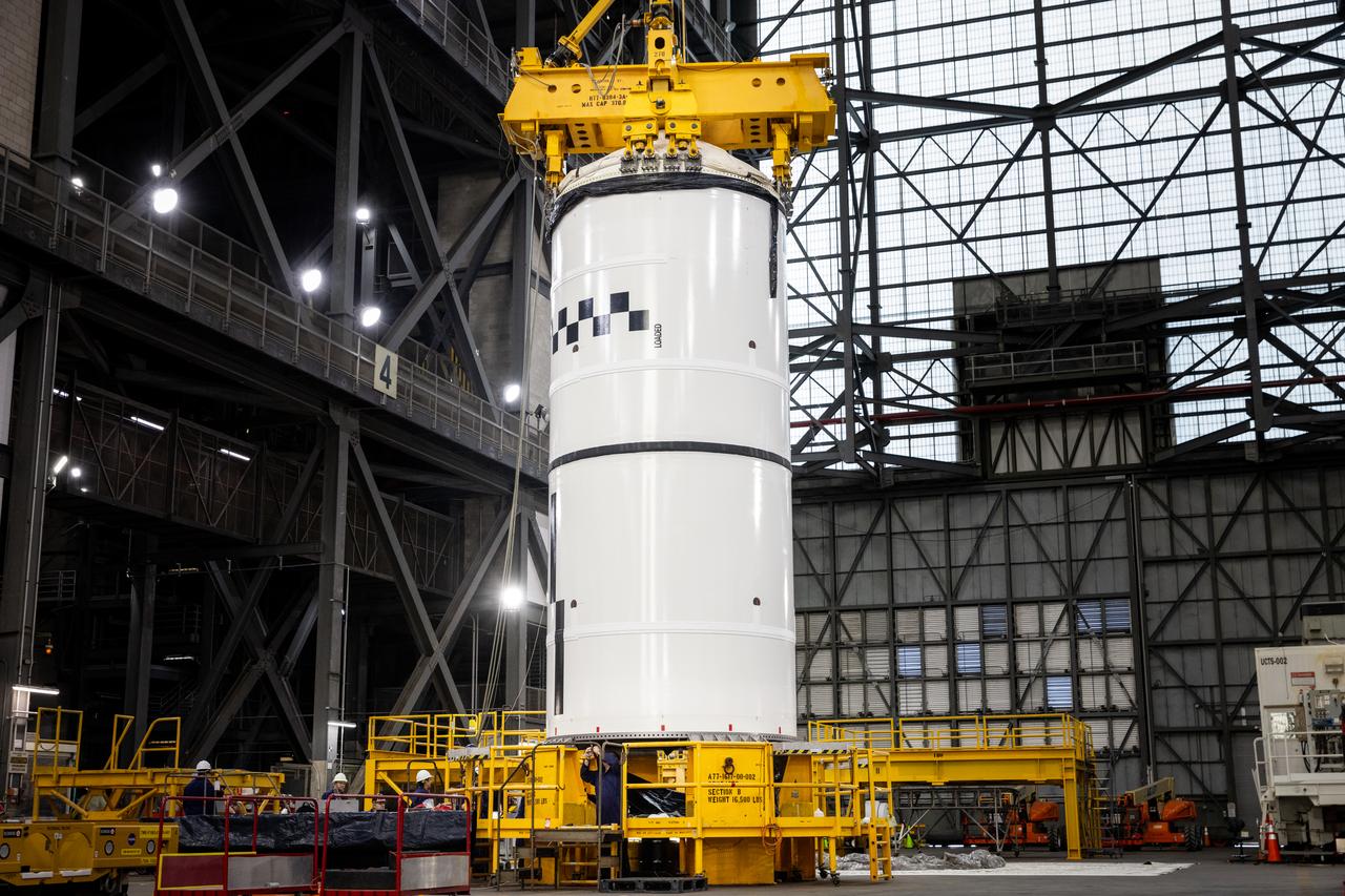 Technicians with NASA’s Exploration Ground Systems use a crane in the transfer aisle of the Vehicle Assembly Building at the agency’s Kennedy Space Center in Florida to prepare to lift the left forward segment for NASA’s SLS (Space Launch System) Moon rocket boosters on Wednesday, Feb. 5, 2025. The left forward segment will be transferred into High Bay 3 where it will be attached to the center forward segment on mobile launcher 1. The twin solid boosters, five segments on each side, will help support the remaining rocket components and the Orion spacecraft during final assembly of the Artemis II Moon rocket and provide more than 75 percent of the total SLS thrust during liftoff from NASA Kennedy’s Launch Pad 39B.