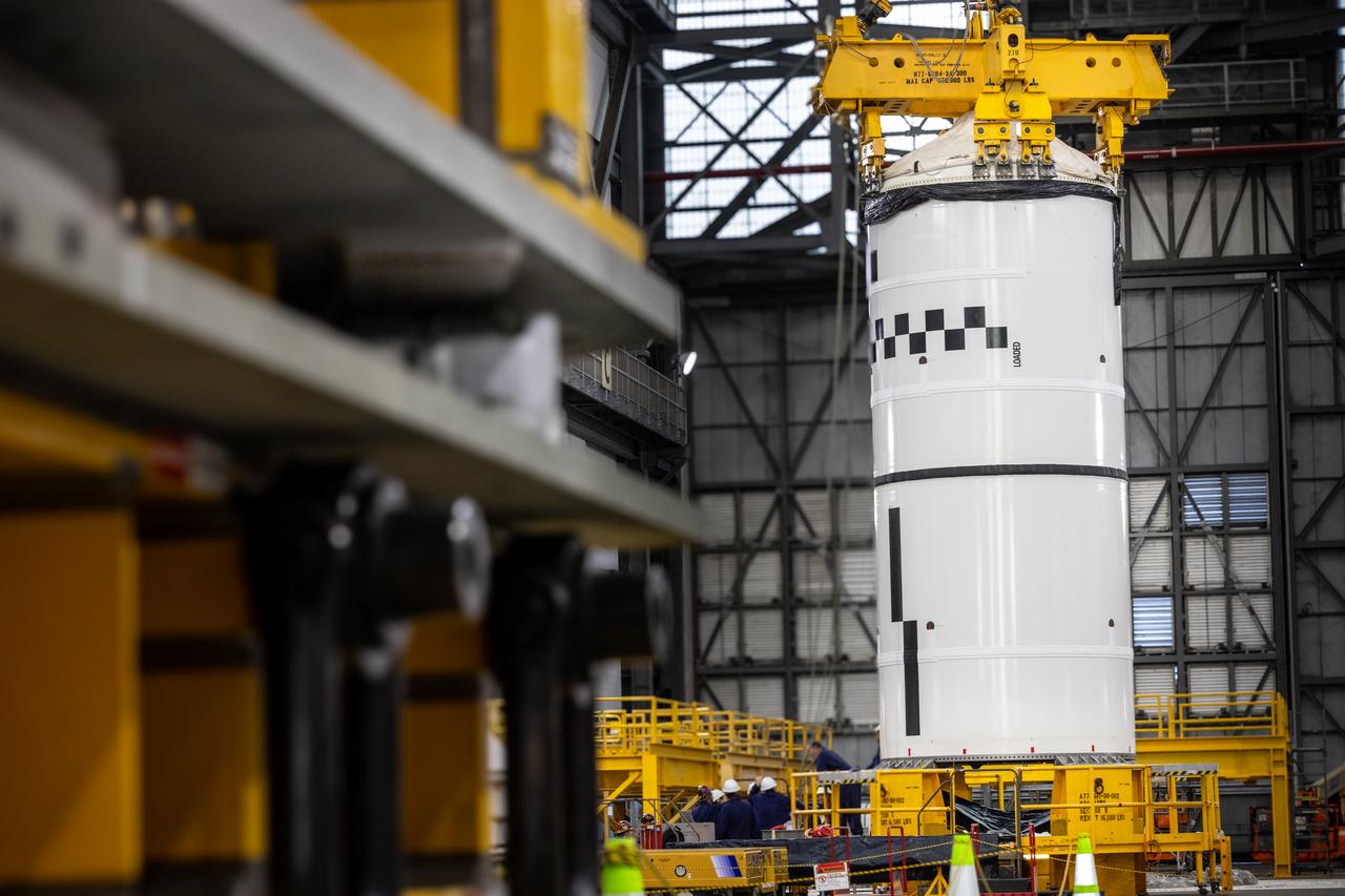 Technicians with NASA’s Exploration Ground Systems use a crane in the transfer aisle of the Vehicle Assembly Building at the agency’s Kennedy Space Center in Florida to prepare to lift the left forward segment for NASA’s SLS (Space Launch System) Moon rocket boosters on Wednesday, Feb. 5, 2025. The left forward segment will be transferred into High Bay 3 where it will be attached to the center forward segment on mobile launcher 1. The twin solid boosters, five segments on each side, will help support the remaining rocket components and the Orion spacecraft during final assembly of the Artemis II Moon rocket and provide more than 75 percent of the total SLS thrust during liftoff from NASA Kennedy’s Launch Pad 39B.
