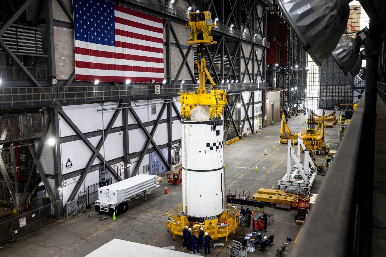 Technicians with NASA’s Exploration Ground Systems use a crane in the transfer aisle of the Vehicle Assembly Building at the agency’s Kennedy Space Center in Florida to prepare to lift the left forward segment for NASA’s SLS (Space Launch System) Moon rocket boosters on Wednesday, Feb. 5, 2025. The left forward segment will be transferred into High Bay 3 where it will be attached to the center forward segment on mobile launcher 1. The twin solid boosters, five segments on each side, will help support the remaining rocket components and the Orion spacecraft during final assembly of the Artemis II Moon rocket and provide more than 75 percent of the total SLS thrust during liftoff from NASA Kennedy’s Launch Pad 39B.