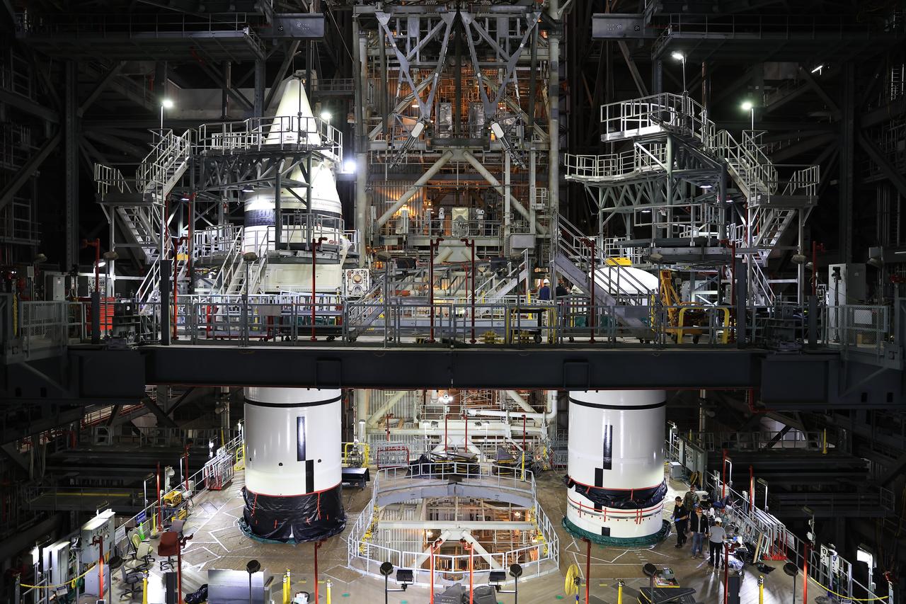 Engineers with NASA’s Exploration Ground Systems integrate the aerodynamic nose cone onto the left-hand forward assembly on the twin SLS (Space Launch System) solid rocket boosters for Artemis II inside the Vehicle Assembly Building’s High Bay 3 at NASA’s Kennedy Space Center in Florida on Tuesday, Feb. 18, 2025. Each forward assembly contains an aerodynamic top, a forward skirt housing avionics, and frustum housing motors that allow the boosters to separate from the SLS core stage after launch. The twin solid boosters will help support the remaining rocket components and the Orion spacecraft during final assembly of the Artemis II Moon rocket and provide more than 75 percent of the total SLS thrust during liftoff from NASA Kennedy’s Launch Pad 39B.