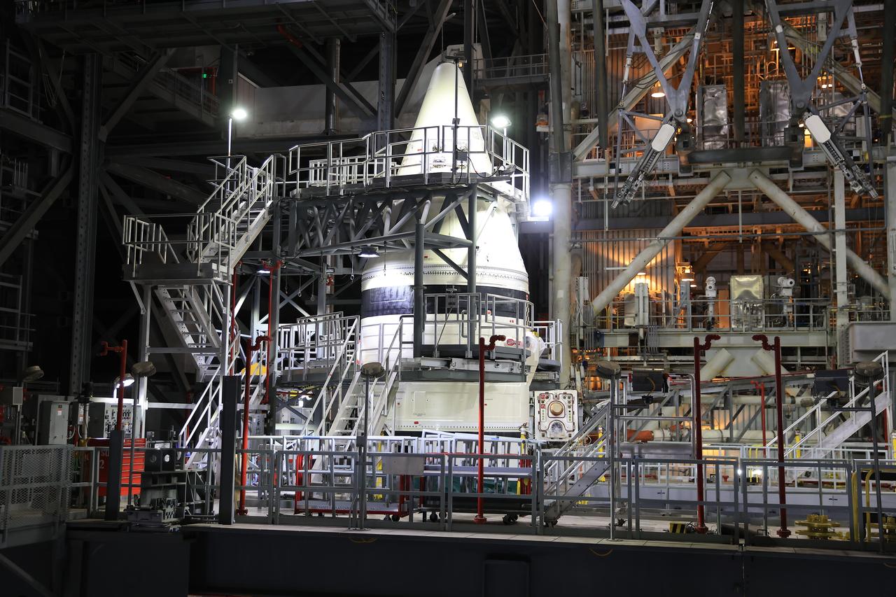 Engineers with NASA’s Exploration Ground Systems integrate the aerodynamic nose cone onto the left-hand forward assembly on the twin SLS (Space Launch System) solid rocket boosters for Artemis II inside the Vehicle Assembly Building’s High Bay 3 at NASA’s Kennedy Space Center in Florida on Tuesday, Feb. 18, 2025. Each forward assembly contains an aerodynamic top, a forward skirt housing avionics, and frustum housing motors that allow the boosters to separate from the SLS core stage after launch. The twin solid boosters will help support the remaining rocket components and the Orion spacecraft during final assembly of the Artemis II Moon rocket and provide more than 75 percent of the total SLS thrust during liftoff from NASA Kennedy’s Launch Pad 39B.