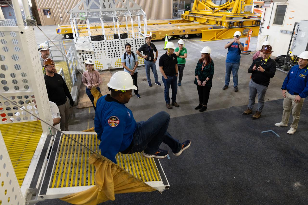NASA astronaut Andre Douglas, Artemis II backup crew member practices climbing out of an emergency egress basket inside the Vehicle Assembly Building at NASA’s Kennedy Space Center in Florida on Thursday, Feb. 27, 2025. The baskets, similar to gondolas on ski lifts, are used in the case of a pad abort emergency to enable astronauts and other pad personnel a way to quickly escape away from the mobile launcher to the base of the pad and where waiting emergency transport vehicles will then drive them away. For Artemis II, four astronauts will venture around the Moon, the first crewed mission on NASA’s path to establishing a long-term presence for science and exploration through Artemis.