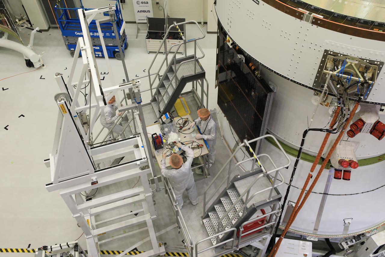 Technicians install four solar array wings on NASA’s Artemis II Orion spacecraft inside the Neil A. Armstrong Operations and Checkout Building at NASA’s Kennedy Space Center in Florida on Monday, March 3, 2025. Each solar array is nearly 23 feet long and can turn on two axes to remain aligned with the Sun for maximum power. Orion’s solar arrays, manufactured and installed by ESA (European Space Agency) and its contractor Airbus, will deliver power to the service module that provides propulsion, thermal control, and electrical power to the spacecraft, as well as air and water for the crew.