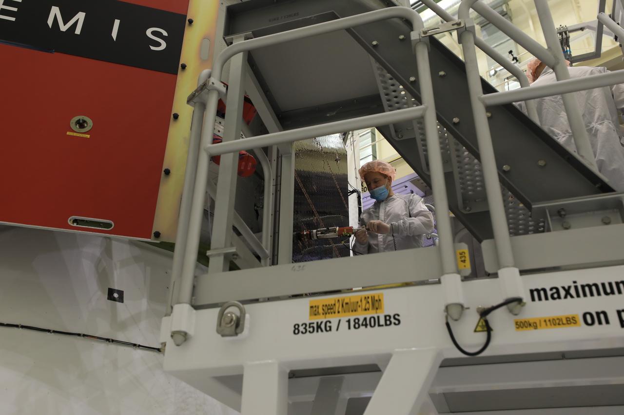 Technicians install four solar array wings on NASA’s Artemis II Orion spacecraft inside the Neil A. Armstrong Operations and Checkout Building at NASA’s Kennedy Space Center in Florida on Monday, March 3, 2025. Each solar array is nearly 23 feet long and can turn on two axes to remain aligned with the Sun for maximum power. Orion’s solar arrays, manufactured and installed by ESA (European Space Agency) and its contractor Airbus, will deliver power to the service module that provides propulsion, thermal control, and electrical power to the spacecraft, as well as air and water for the crew.