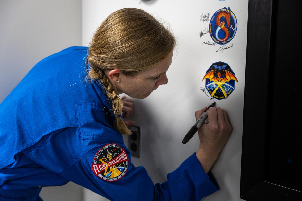 NASA astronaut Nichole Ayers signs her name inside the Astronaut Crew Quarters in the Neil A. Armstrong Operations and Checkout Building at NASA’s Kennedy Space Center in Florida on Friday, March 7, 2025, ahead of NASA’s SpaceX Crew-10 mission. Crew-10 is the 10th crew rotation mission of the SpaceX Dragon spacecraft and Falcon 9 rocket that will send Ayers and fellow NASA astronaut Anne McClain, along with JAXA (Japan Aerospace Exploration Agency) astronaut Takuya Onishi and Roscosmos cosmonaut Kirill Peskov to the International Space Station as part of the agency’s Commercial Crew Program. The mission is scheduled to launch no earlier than 7:48 p.m. EDT on Wednesday, March 12, 2025, from NASA Kennedy’s Launch Complex 39A.
