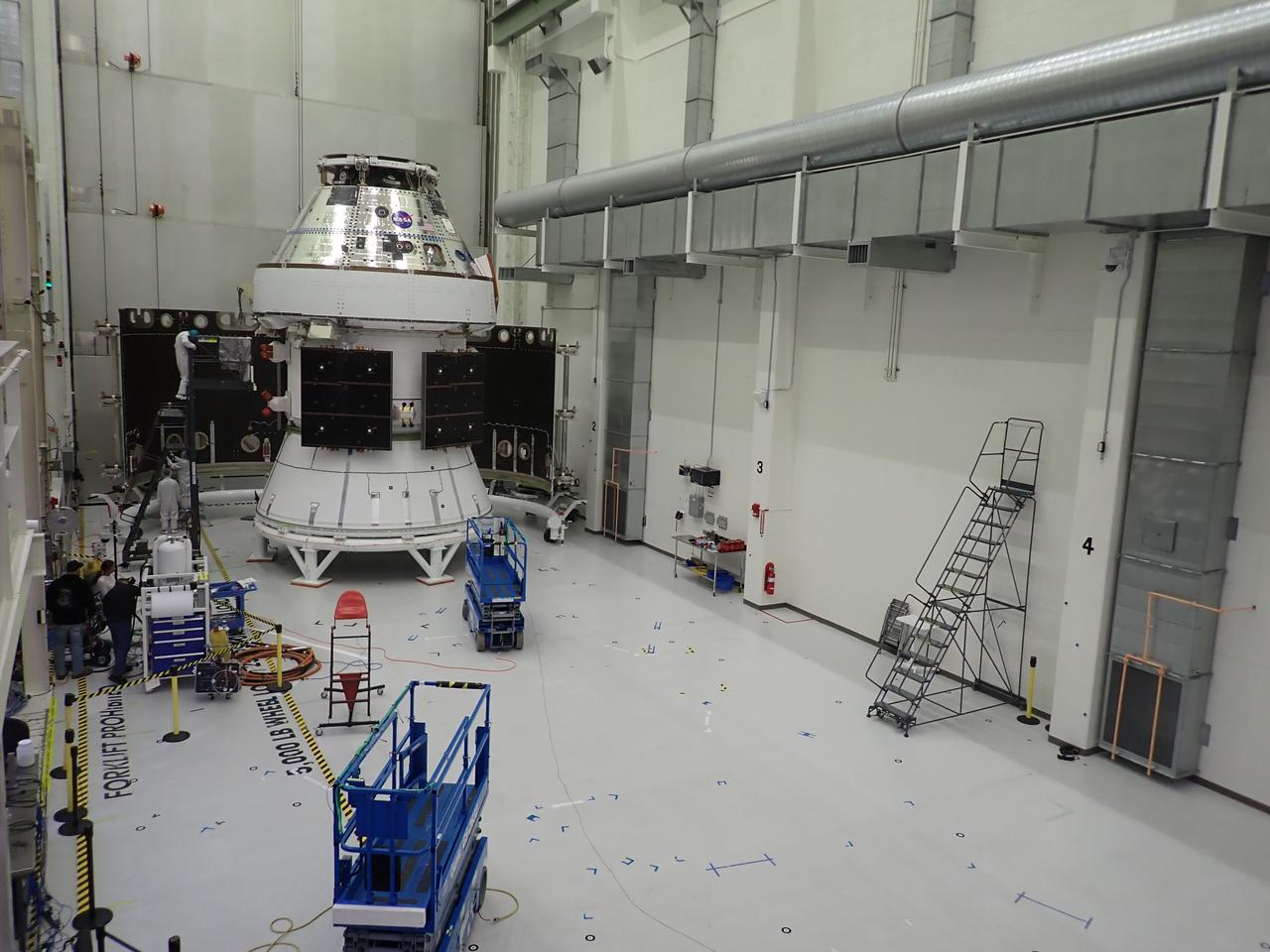 Technicians with Lockheed Martin prepare the Artemis II Orion spacecraft for the installation of three spacecraft adapter jettison fairings inside the Neil A. Armstrong Operations and Checkout Building at NASA’s Kennedy Space Center in Florida in on Tuesday, March 11, 2025. The fairings encapsulate the service module and protect the solar array wings, shielding them from the heat, wind, and acoustics of launch and ascent, plus help redistribute the load between Orion and the massive thrust of the SLS (Space Launch System) rocket during liftoff and ascent. Once the spacecraft is above the atmosphere, the three fairing panels will separate from the service module reducing the mass of the spacecraft. 