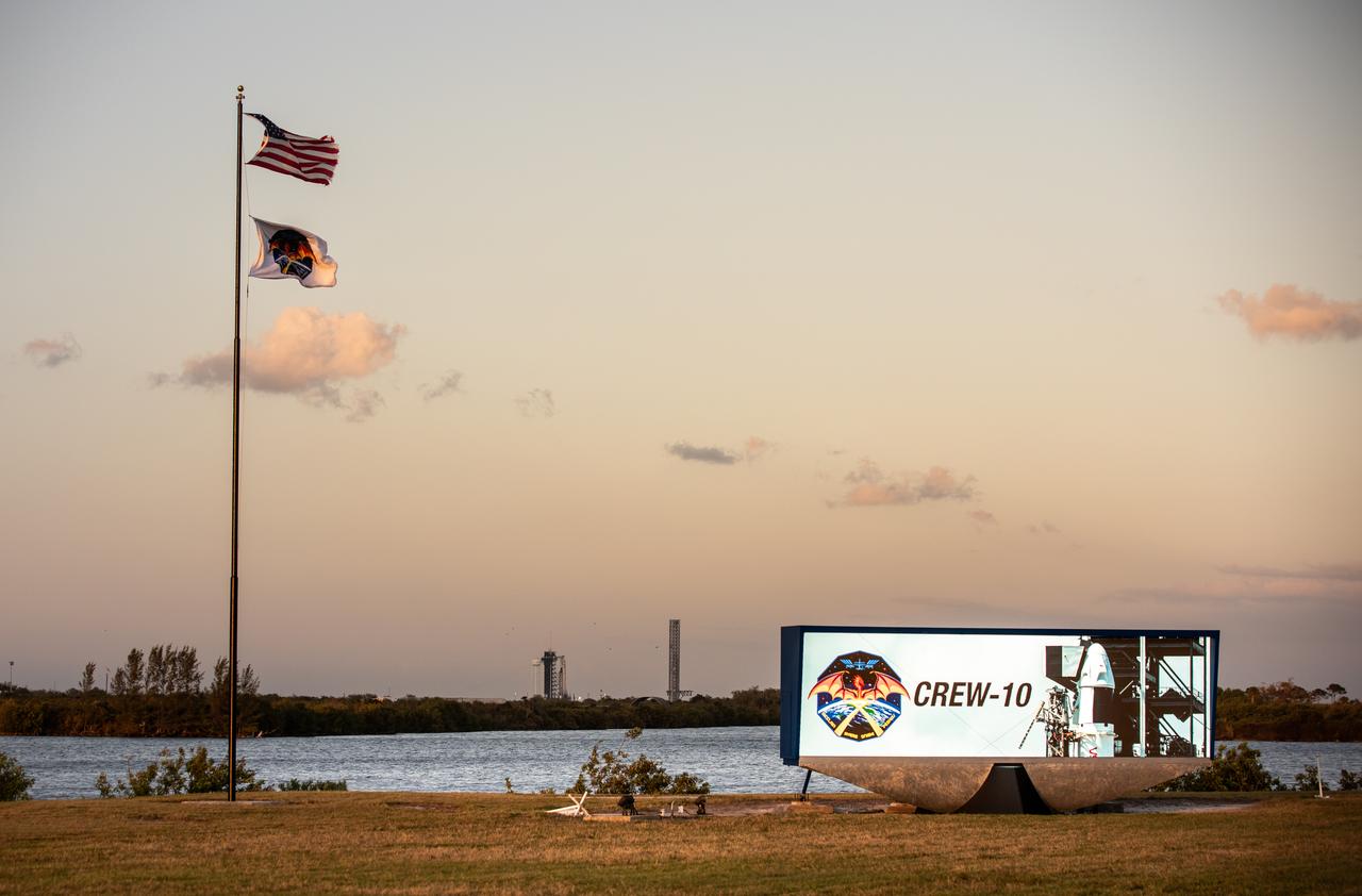 NASA Commercial Crew Program employees raise the agency’s SpaceX Crew-10 mission flag near the countdown clock at the NASA News Center at the agency’s Kennedy Space Center in Florida on Monday, March 10, 2025. The Crew-10 mission will send NASA astronauts Anne McClain and Nichole Ayers, along with JAXA (Japan Aerospace Exploration Agency) astronaut Takuya Onishi and Roscosmos cosmonaut Kirill Peskov to the International Space Station aboard SpaceX’s Dragon spacecraft and Falcon 9 rocket. Launch is targeted for 7:48 p.m. EDT on Wednesday, March 12, 2025, from Launch Complex 39A at NASA Kennedy. Crew-10 is the 10th crew rotation mission with SpaceX to the space station as part of the agency’s Commercial Crew Program.