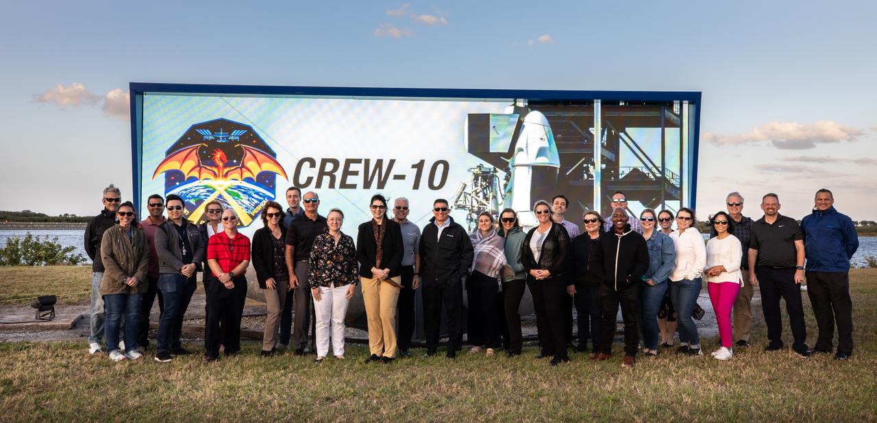 NASA Commercial Crew Program employees raise the agency’s SpaceX Crew-10 mission flag near the countdown clock at the NASA News Center at the agency’s Kennedy Space Center in Florida on Monday, March 10, 2025. The Crew-10 mission will send NASA astronauts Anne McClain and Nichole Ayers, along with JAXA (Japan Aerospace Exploration Agency) astronaut Takuya Onishi and Roscosmos cosmonaut Kirill Peskov to the International Space Station aboard SpaceX’s Dragon spacecraft and Falcon 9 rocket. Launch is targeted for 7:48 p.m. EDT on Wednesday, March 12, 2025, from Launch Complex 39A at NASA Kennedy. Crew-10 is the 10th crew rotation mission with SpaceX to the space station as part of the agency’s Commercial Crew Program.