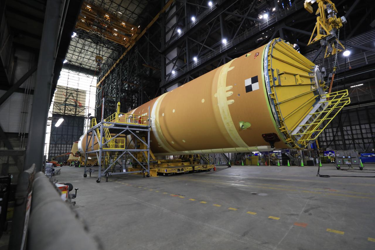 Technicians from NASA’s Exploration Ground Systems use massive cranes inside the agency’s Vehicle Assembly Building (VAB) to lift the fully assembled SLS (Space Launch System) core stage vertically 225 feet above the ground from High Bay 2 to a horizontal position in the facility’s transfer aisle at NASA’s Kennedy Space Center in Florida on Friday, March 14, 2025. The 212-foot core stage will undergo final checkouts before being lifted into the VAB’s High Bay 3 for integration alongside the completed stack of twin solid rocket booster segments.