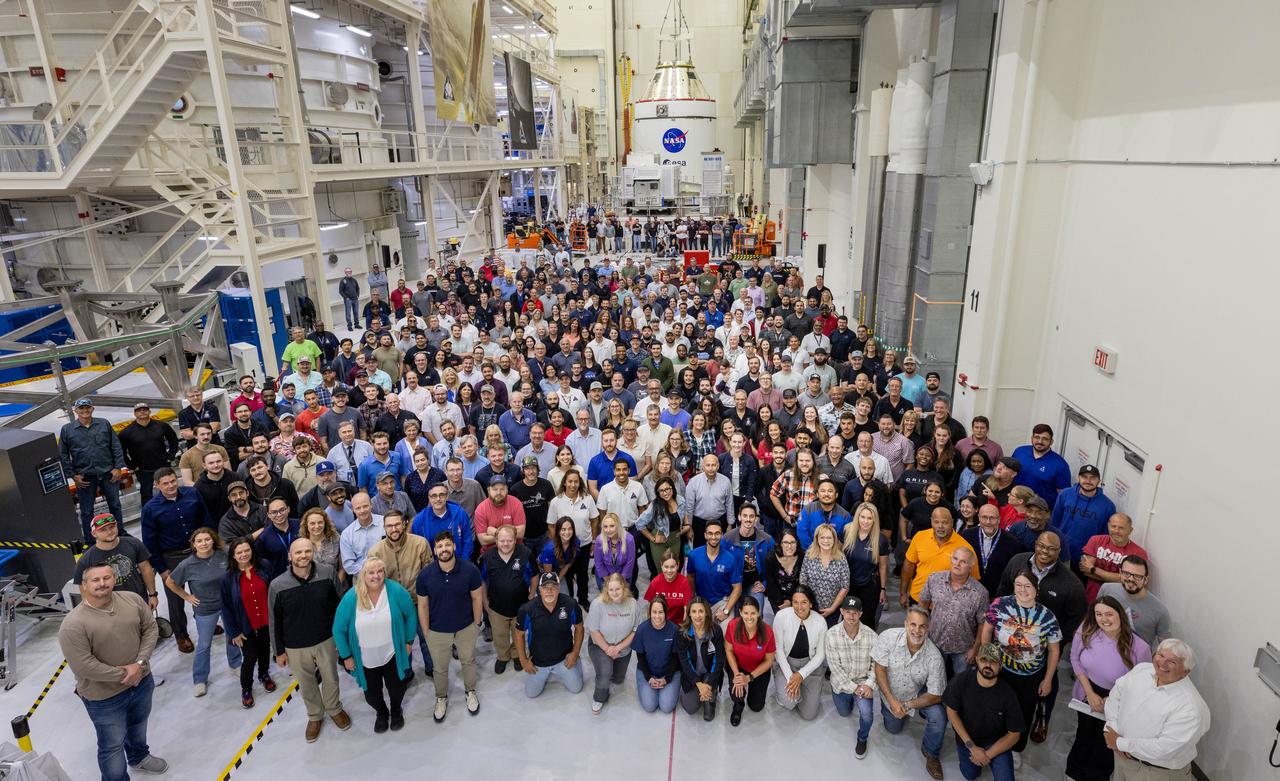 Teams from NASA and Lockheed Martin pose for a photo in front of NASA’s Artemis II Orion spacecraft, connected to a massive crane ahead atop the agency’s KAMAG transporter inside the Neil A. Operations and Checkout Building at NASA’s Kennedy Space Center in Florida on Friday, May 2, 2025. The spacecraft will be transported to the spaceport’s Multi-Payload Processing Facility to undergo fueling and processing for prelaunch operations. The Artemis II test flight is the first crewed flight under NASA’s Artemis campaign and is another step toward missions on the lunar surface and helping the agency prepare for future human missions to Mars.