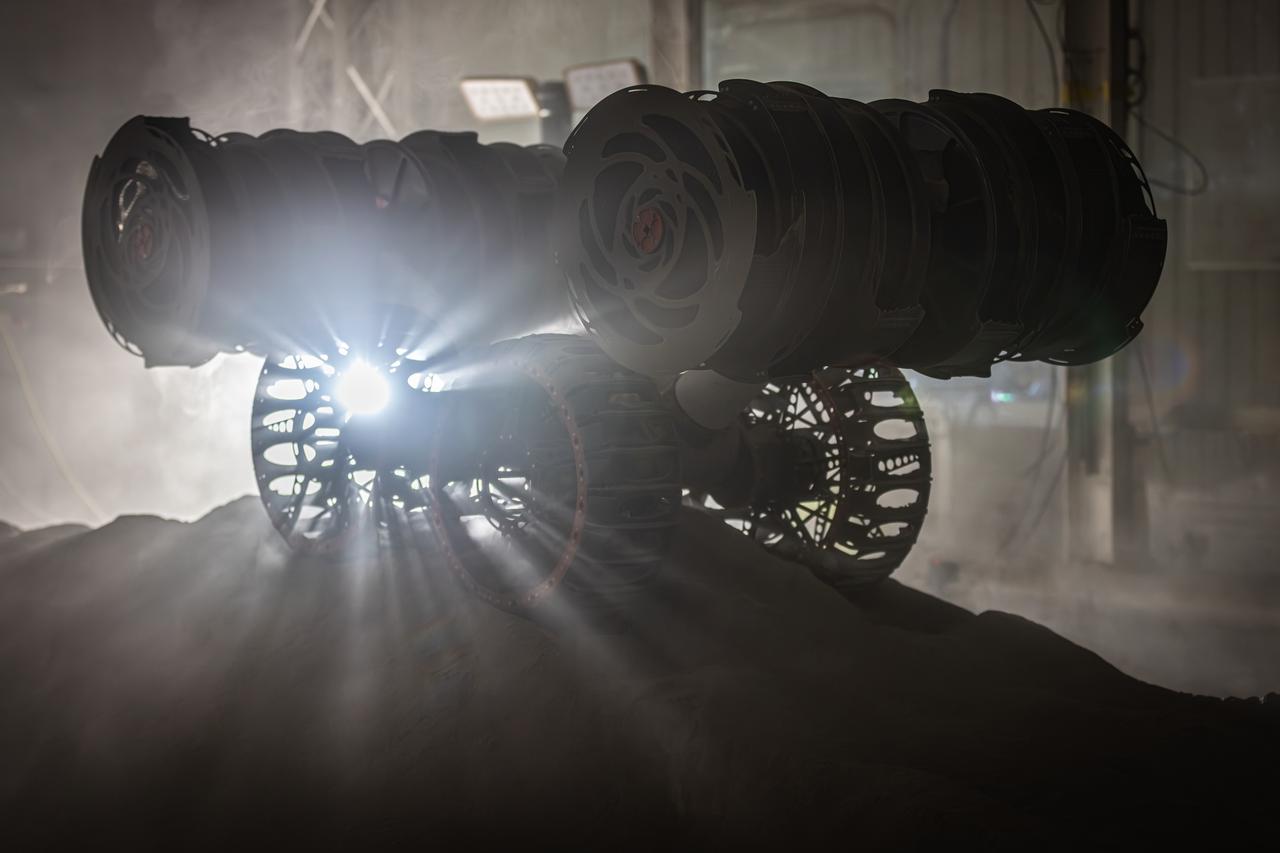 NASA’s RASSOR (Regolith Advanced Surface Systems Operations Robot) conducts excavation testing of simulated regolith, or lunar dust found on the Moon’s surface, inside of the Granular Mechanics and Regolith Operations Lab at the agency’s Kennedy Space Center in Florida on Tuesday, May 27, 2025. RASSOR is designed to work in low-gravity situations, using counter rotating bucket drums on each arm to collect and dump regolith for the extraction of hydrogen, oxygen, or water, resources critical for sustaining a habitable presence.