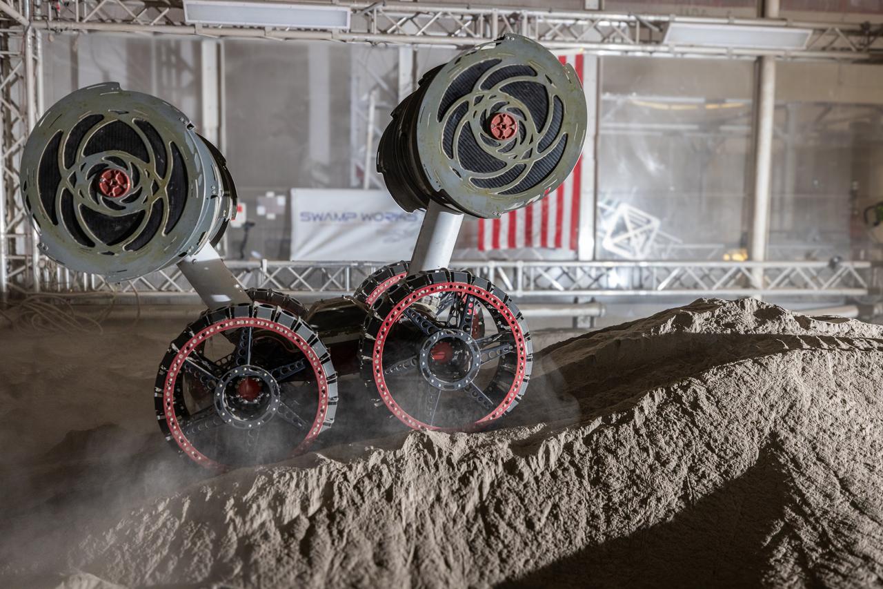 NASA’s RASSOR (Regolith Advanced Surface Systems Operations Robot) conducts excavation testing of simulated regolith, or lunar dust found on the Moon’s surface, inside of the Granular Mechanics and Regolith Operations Lab at the agency’s Kennedy Space Center in Florida on Tuesday, May 27, 2025. RASSOR is designed to work in low-gravity situations, using counter rotating bucket drums on each arm to collect and dump regolith for the extraction of hydrogen, oxygen, or water, resources critical for sustaining a habitable presence.