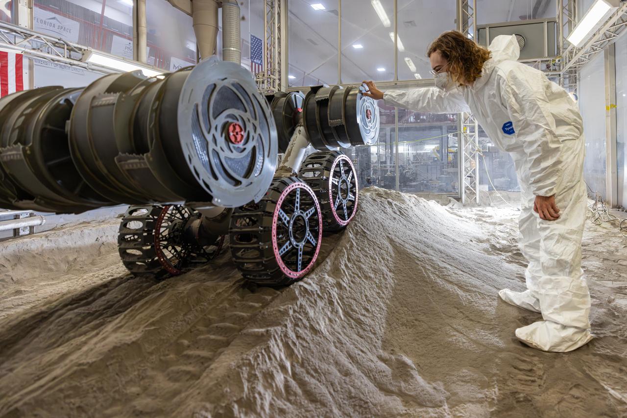 Ben Burdess, mechanical engineer, observes NASA’s RASSOR (Regolith Advanced Surface Systems Operations Robot) excavation testing of simulated regolith, or lunar dust found on the Moon’s surface, inside of the Granular Mechanics and Regolith Operations Lab at the agency’s Kennedy Space Center in Florida on Tuesday, May 27, 2025. RASSOR is designed to work in low-gravity situations, using counter rotating bucket drums on each arm to collect and dump regolith for the extraction of hydrogen, oxygen, or water, resources critical for sustaining a habitable presence.