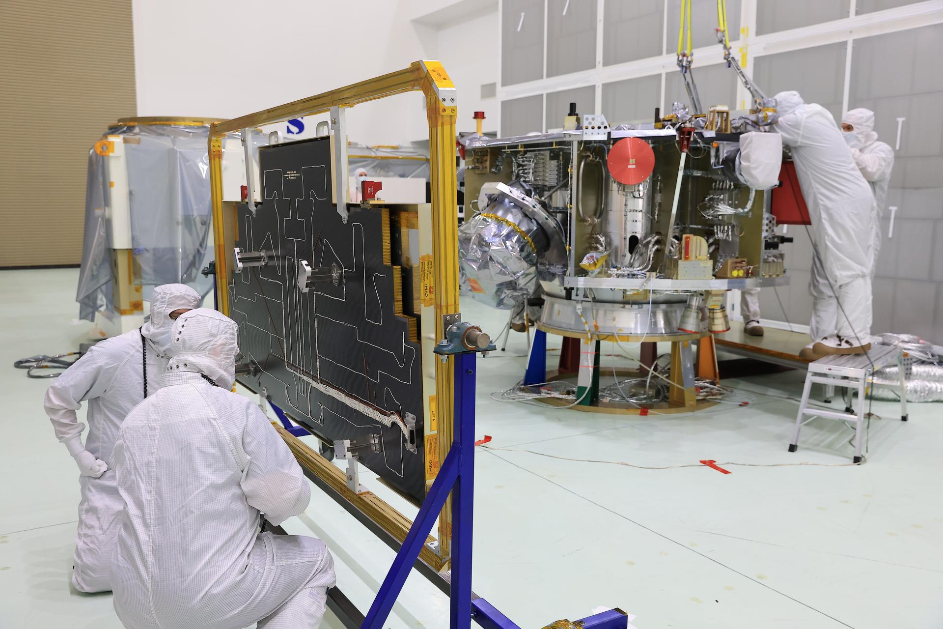 Technicians in cleanroom suits install the two-panel solar array on NASA's IMAP (Interstellar Mapping and Acceleration Probe) observatory.