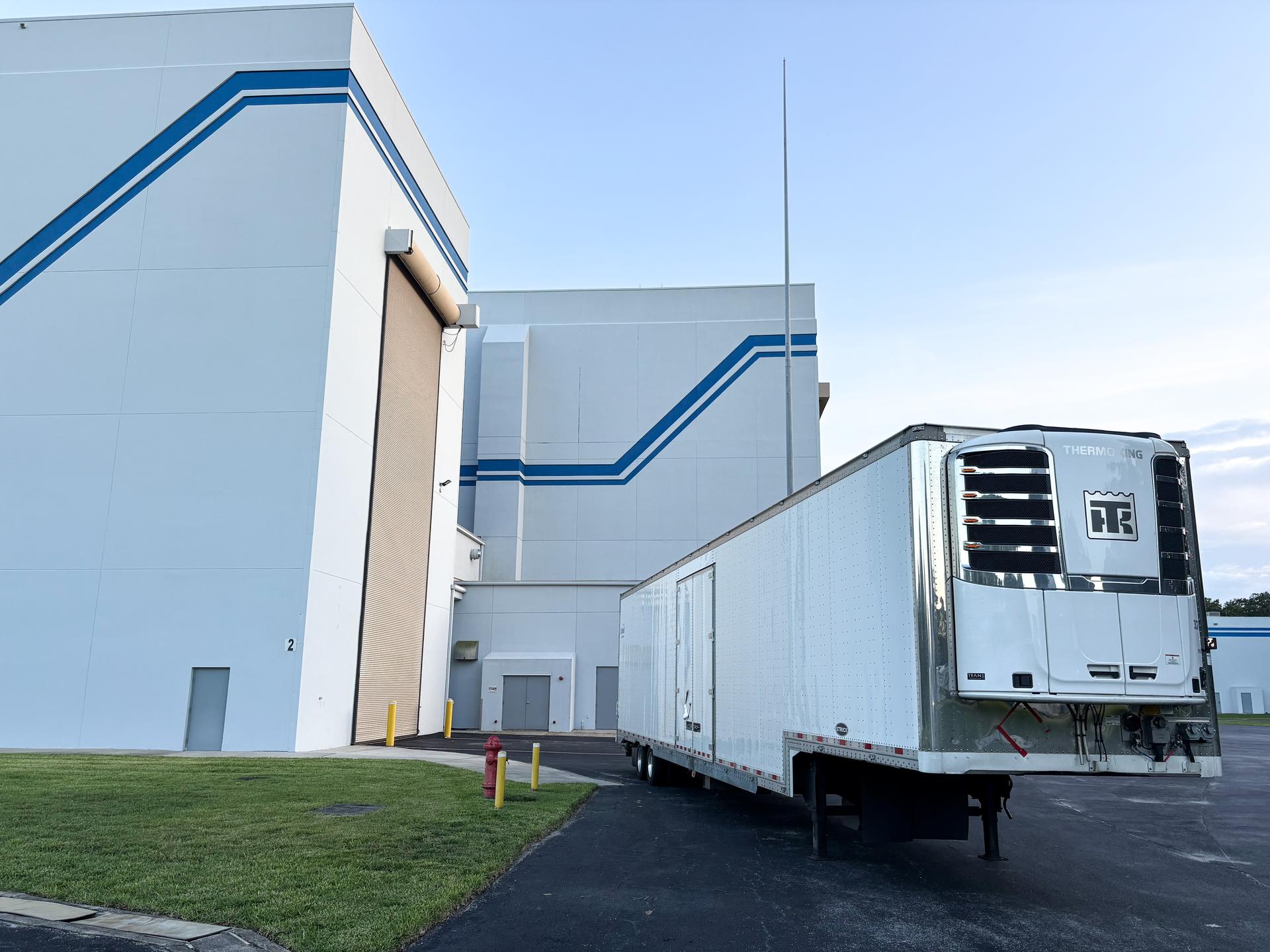 Image shows a semi-truck trailer carrying a satellite for NASA.