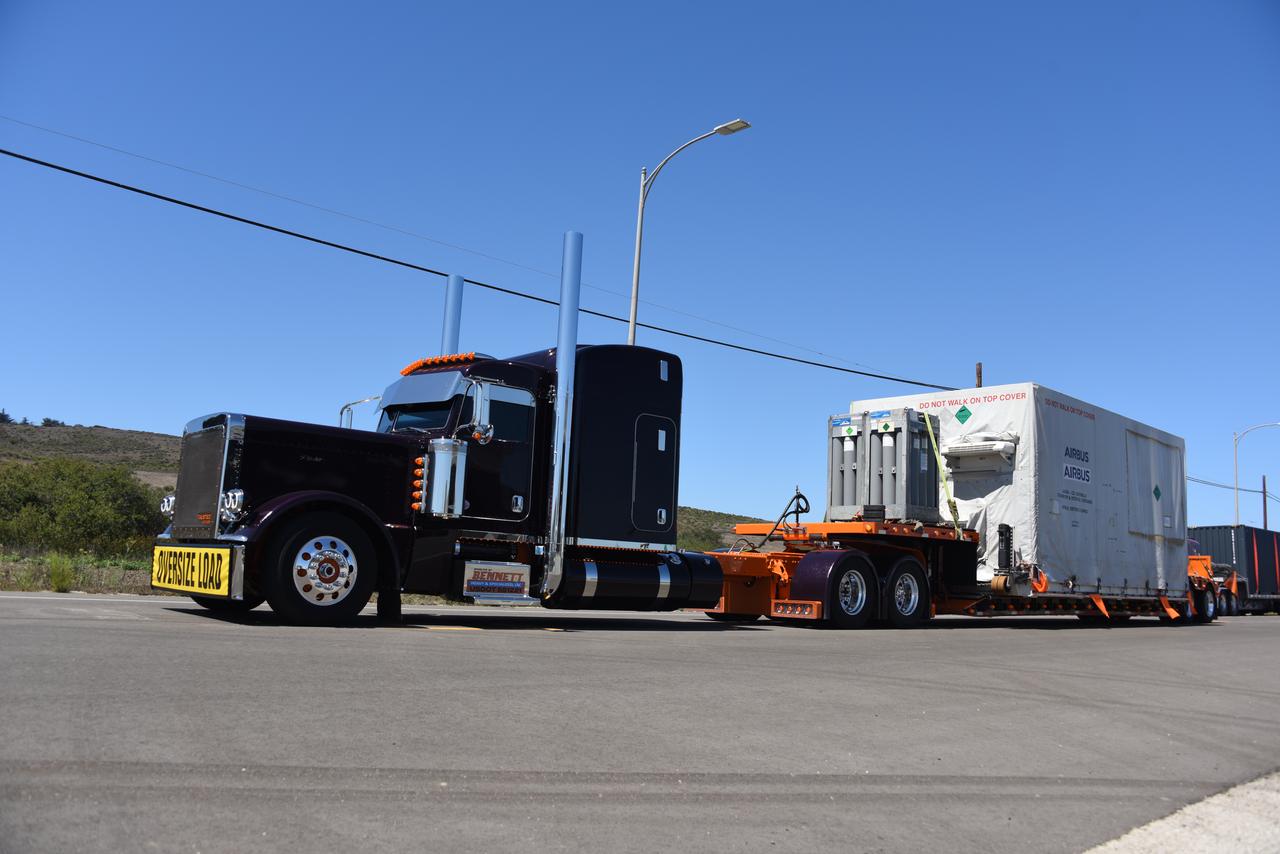 Packed in its shipping container, the Sentinel-6B spacecraft, a collaboration between NASA, ESA (European Space Agency), EUMETSAT (European Organisation for the Exploitation of Meteorological Satellites), and the National Oceanic and Atmospheric Administration (NOAA), arrives by truck at the entrance NASA’s Building 836 at Vandenberg Space Force Base in California on Monday, Aug. 18, 2025. The second of two spacecraft that constitutes the Sentinel-6/Jason-CS (Continuity of Service) mission, Sentinel-6B will measure sea surface height and provide crucial information to help improve coastal planning, enabling local and state governments to make informed decisions about protecting coastal infrastructure, real estate, and energy sites. Launch is targeted for no earlier than November on a SpaceX Falcon 9 from Vandenberg.
