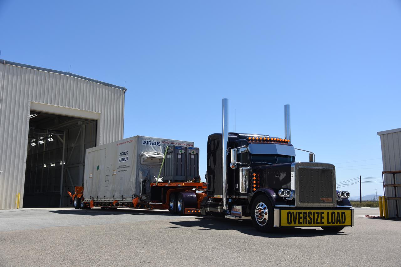 Packed in its shipping container, the Sentinel-6B spacecraft, a collaboration between NASA, ESA (European Space Agency), EUMETSAT (European Organisation for the Exploitation of Meteorological Satellites), and the National Oceanic and Atmospheric Administration (NOAA), arrives by truck at the entrance NASA’s Building 836 at Vandenberg Space Force Base in California on Monday, Aug. 18, 2025. The second of two spacecraft that constitutes the Sentinel-6/Jason-CS (Continuity of Service) mission, Sentinel-6B will measure sea surface height and provide crucial information to help improve coastal planning, enabling local and state governments to make informed decisions about protecting coastal infrastructure, real estate, and energy sites. Launch is targeted for no earlier than November on a SpaceX Falcon 9 from Vandenberg.