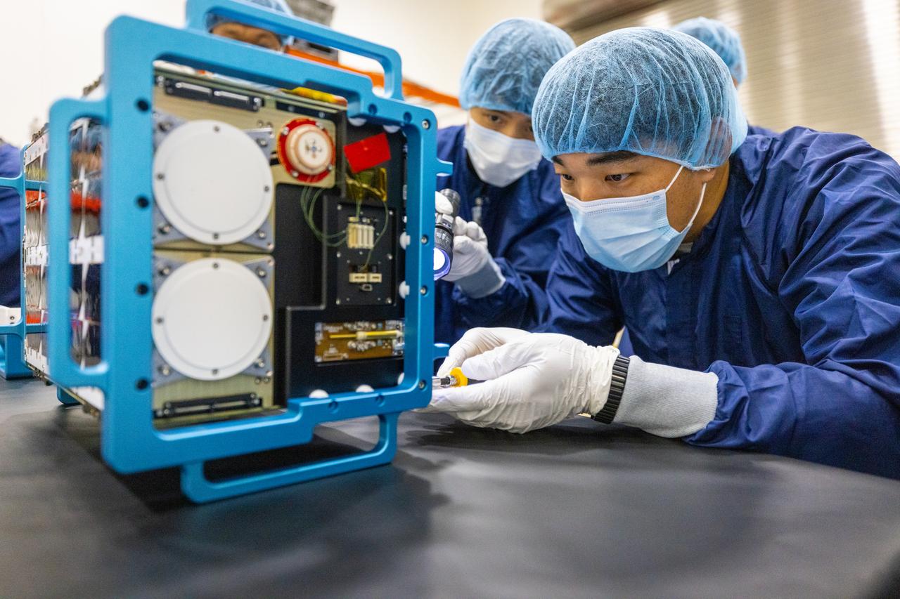 Inside the Multi-Payload Processing Facility at NASA’s Kennedy Space Center in Florida, on Tuesday, Aug. 26, 2025, technicians with the Korea AeroSpace Administration (KASA) inspect the K-Rad Cube, one of several international CubeSats slated to fly on NASA’s Artemis II test flight in 2026. Deploying in high Earth orbit from a spacecraft adapter on NASA’s SLS (Space Launch System) rocket after Orion is safely flying on its own with its crew of four astronauts, K-Rad Cube will use a dosimeter made of material designed to mimic human tissue to measure space radiation and assess biological effects at various altitudes across the Van Allen radiation belts, a critical area of research for human presence at the Moon and Mars.
