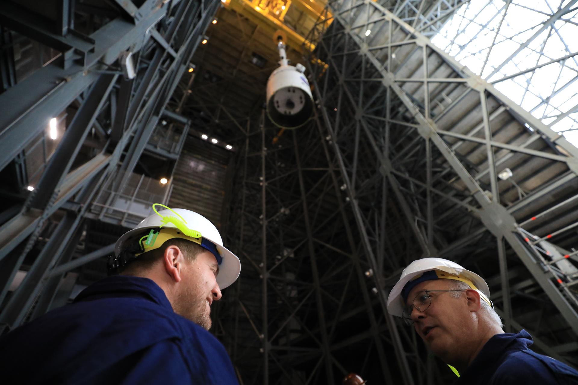 Technicians with NASA’s Exploration Ground Systems team use a crane to lift a...