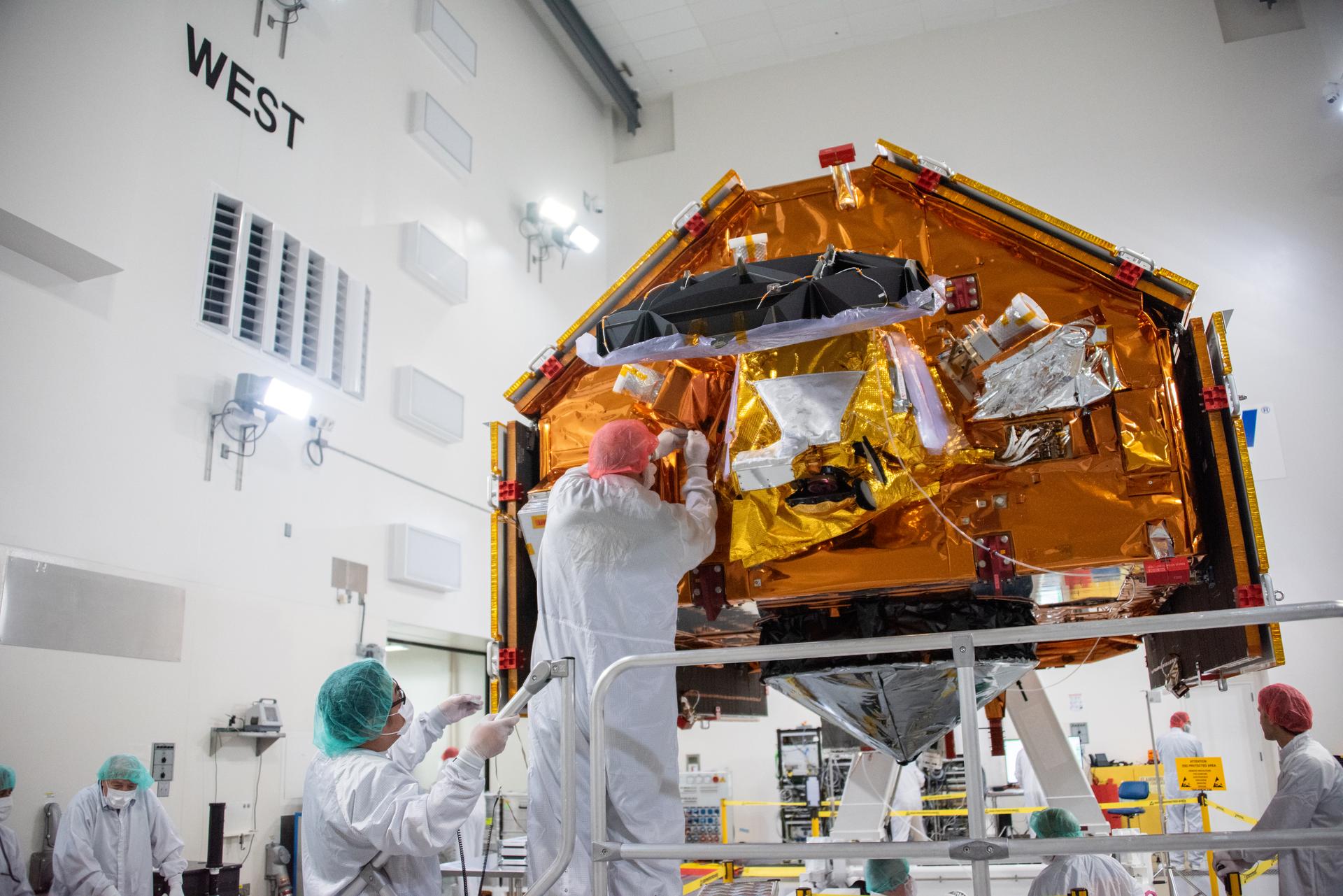 Technicians install multi-layer insulation on the Sentinel-6B spacecraft on a work stand inside the Astrotech Space Operations payload processing facility at Vandenberg Space Force Base in California on Thursday, Oct. 23, 2025. Critical for protecting spacecraft from extreme temperatures and environmental conditions in space, the thin, reflective multi-layer insulation will create a barrier to help reduce heat transfer through radiation while Sentinel-6B is in orbit. A collaboration between NASA, ESA (European Space Agency), EUMETSAT (European Organisation for the Exploitation of Meteorological Satellites), and the National Oceanic and Atmospheric Administration (NOAA), Sentinel-6B is designed to measure sea levels down to roughly an inch for about 90% of the world’s oceans. NASA is targeting launch no earlier than Sunday, Nov. 16, 2025, on a SpaceX Falcon 9 rocket from Space Launch Complex 4 East at Vandenberg.