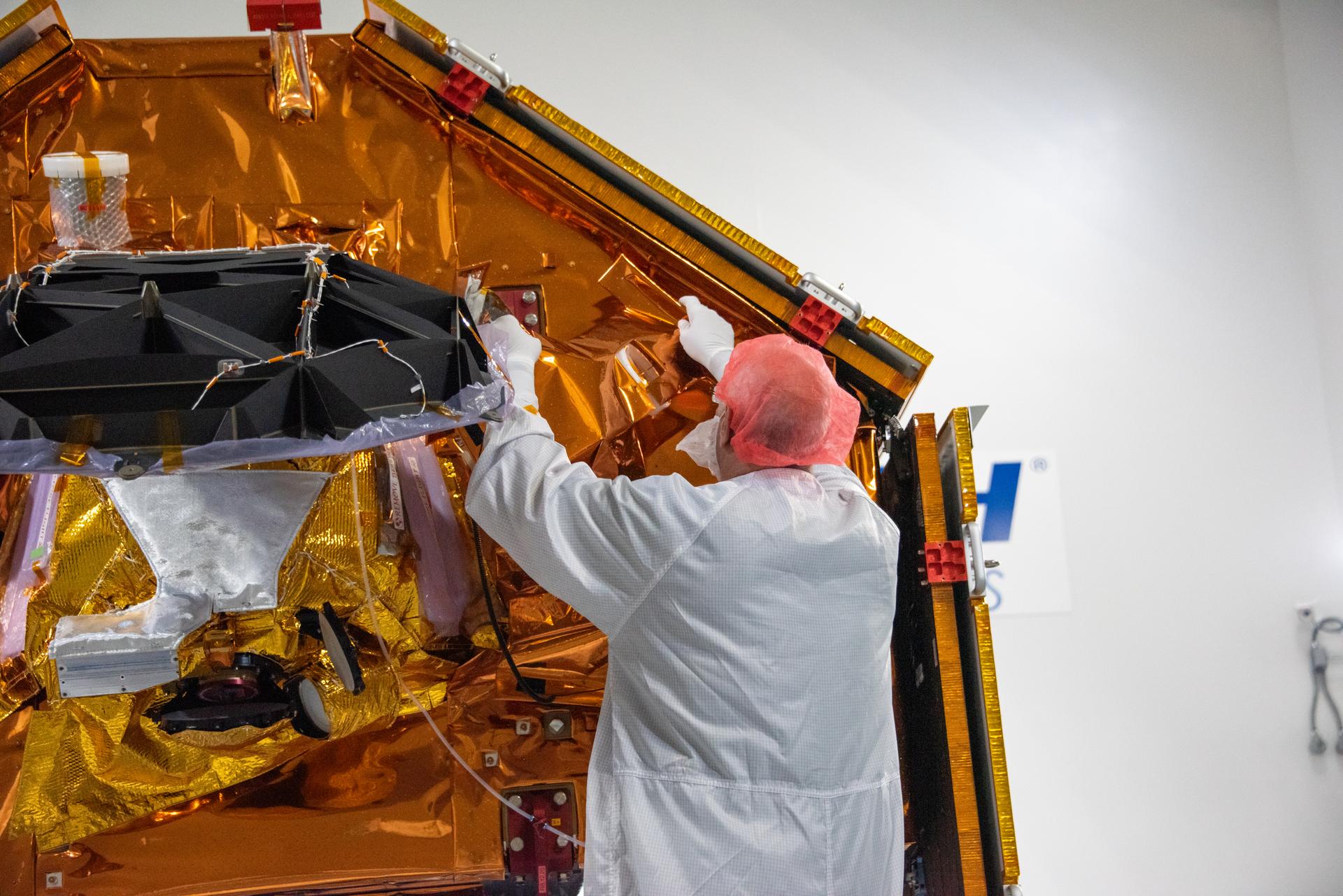 Technicians install multi-layer insulation on the Sentinel-6B spacecraft on a work stand inside the Astrotech Space Operations payload processing facility at Vandenberg Space Force Base in California on Thursday, Oct. 23, 2025. Critical for protecting spacecraft from extreme temperatures and environmental conditions in space, the thin, reflective multi-layer insulation will create a barrier to help reduce heat transfer through radiation while Sentinel-6B is in orbit. A collaboration between NASA, ESA (European Space Agency), EUMETSAT (European Organisation for the Exploitation of Meteorological Satellites), and the National Oceanic and Atmospheric Administration (NOAA), Sentinel-6B is designed to measure sea levels down to roughly an inch for about 90% of the world’s oceans. NASA is targeting launch no earlier than Sunday, Nov. 16, 2025, on a SpaceX Falcon 9 rocket from Space Launch Complex 4 East at Vandenberg.