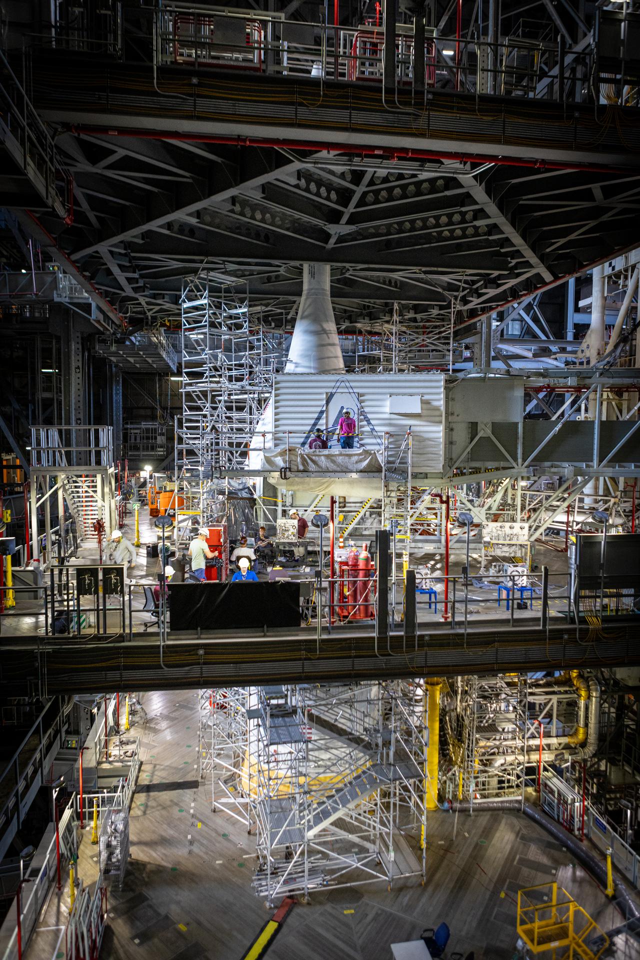 From left, Sean McCrary and Katie Mortensen, mechanical engineering technicians, paint NASA’s Artemis logo on the White Room connected to the crew access arm and mobile launcher inside the Vehicle Assembly Building at NASA’s Kennedy Space Center in Florida on Thursday, Dec. 4, 2025. The White Room is the area where the Artemis II crew Reid Wiseman, Victor Glover, Christina Koch, and CSA (Canadian Space Agency) astronaut Jeremy Hansen will enter the Orion spacecraft ahead of launch from Launch Complex 39B at NASA Kennedy in early 2026.