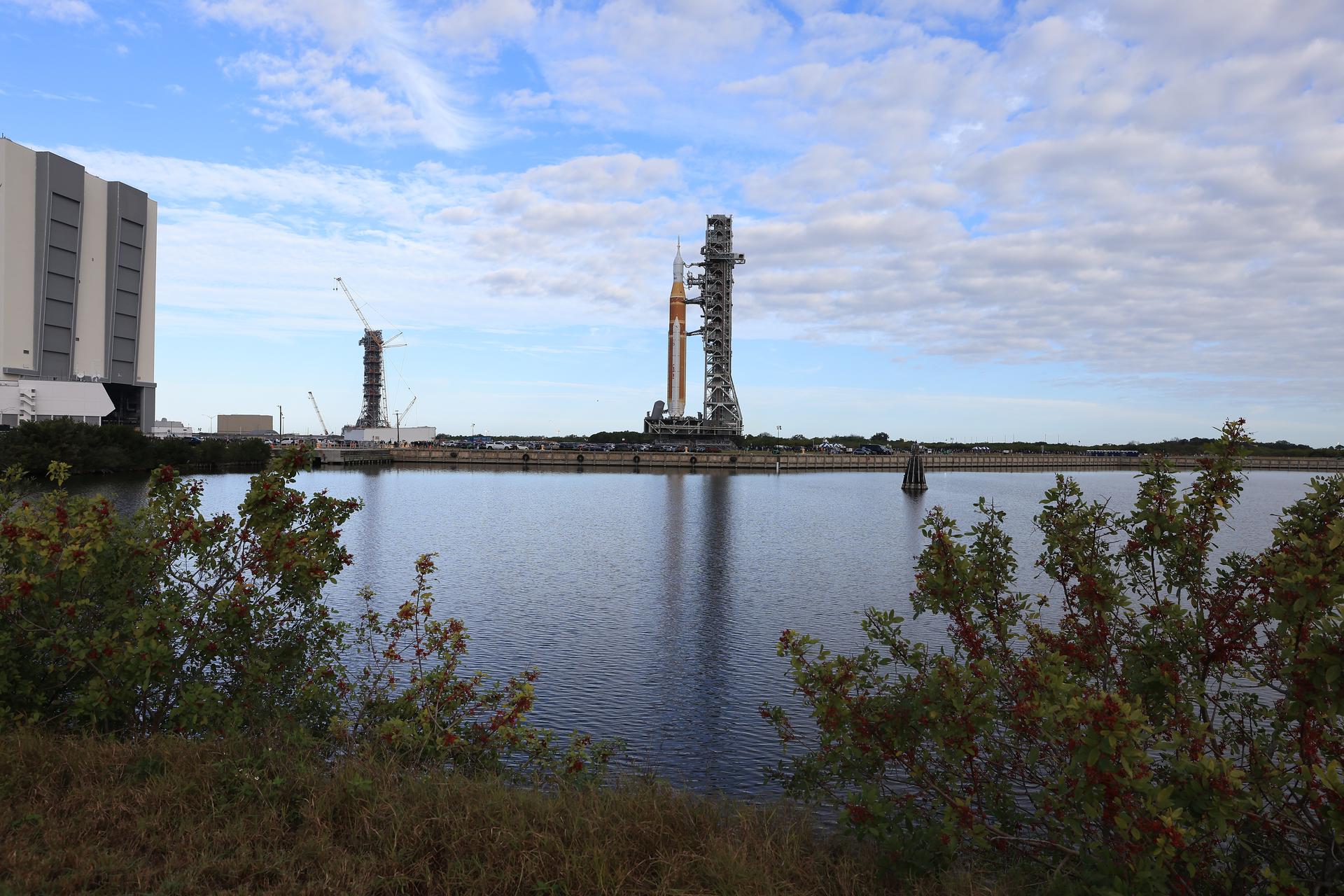 NASA’s crawler-transporter 2 carrying the agency’s Artemis II SLS (Space Launch System) rocket and Orion spacecraft, secured to the mobile launcher, begins rolling out from High Bay 3 inside the Vehicle Assembly Building to Launch Complex 39B at NASA’s Kennedy Space Center in Florida on Saturday, Jan. 17, 2026. Seen in the background is also mobile launcher 2, which will be used on future Artemis flights beginning with Artemis IV. The Artemis II test flight will take Commander Reid Wiseman, Pilot Victor Glover, and Mission Specialist Christina Koch from NASA and Mission Specialist Jeremy Hansen from the CSA (Canadian Space Agency), around the Moon and back to Earth no later than April 2026.